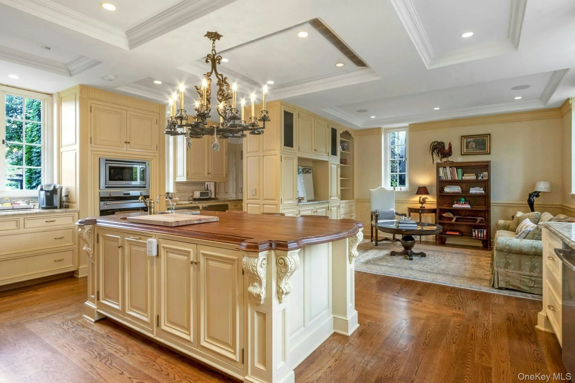 Kitchen featuring cream cabinets, wood finished floors, a kitchen island with sink, a chandelier, and recessed lighting Kitchen featuring cream cabinets, wood finished floors, a kitchen island with sink, a chandelier, and recessed lighting