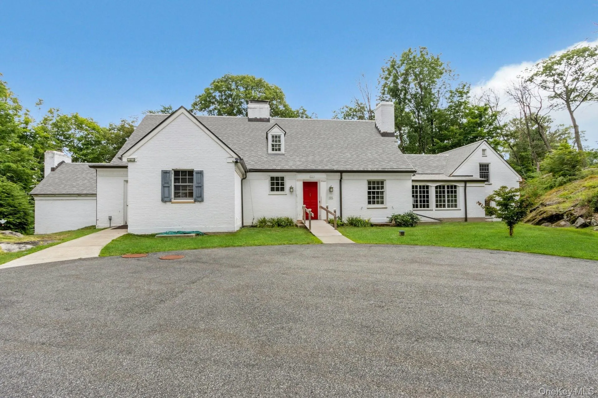 Cape cod home with a chimney, brick siding, a front yard, and roof with shingles Cape cod home with a chimney, brick siding, a front yard, and roof with shingles