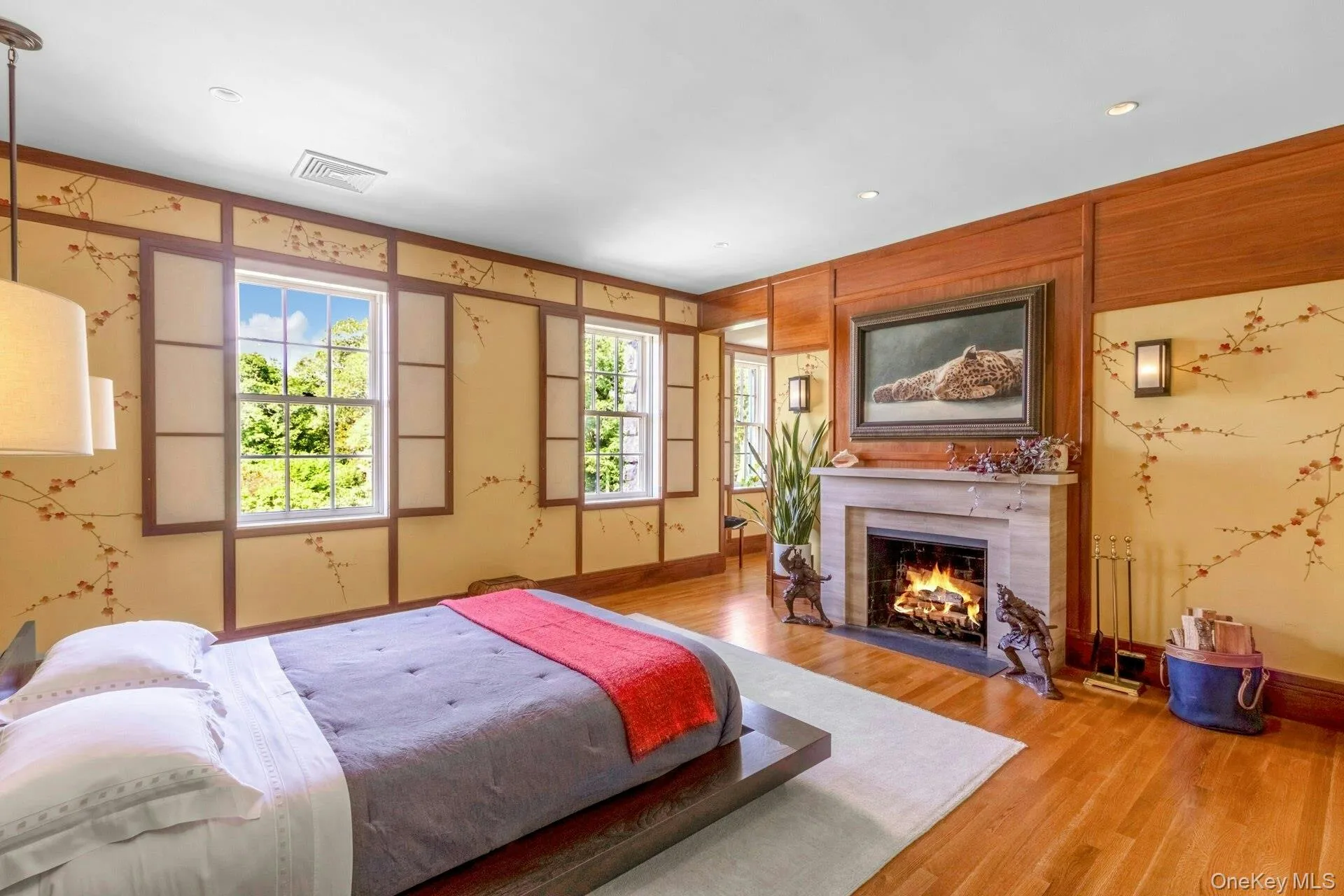 Bedroom with a warm lit fireplace, wood finished floors, and recessed lighting Bedroom with a warm lit fireplace, wood finished floors, and recessed lighting