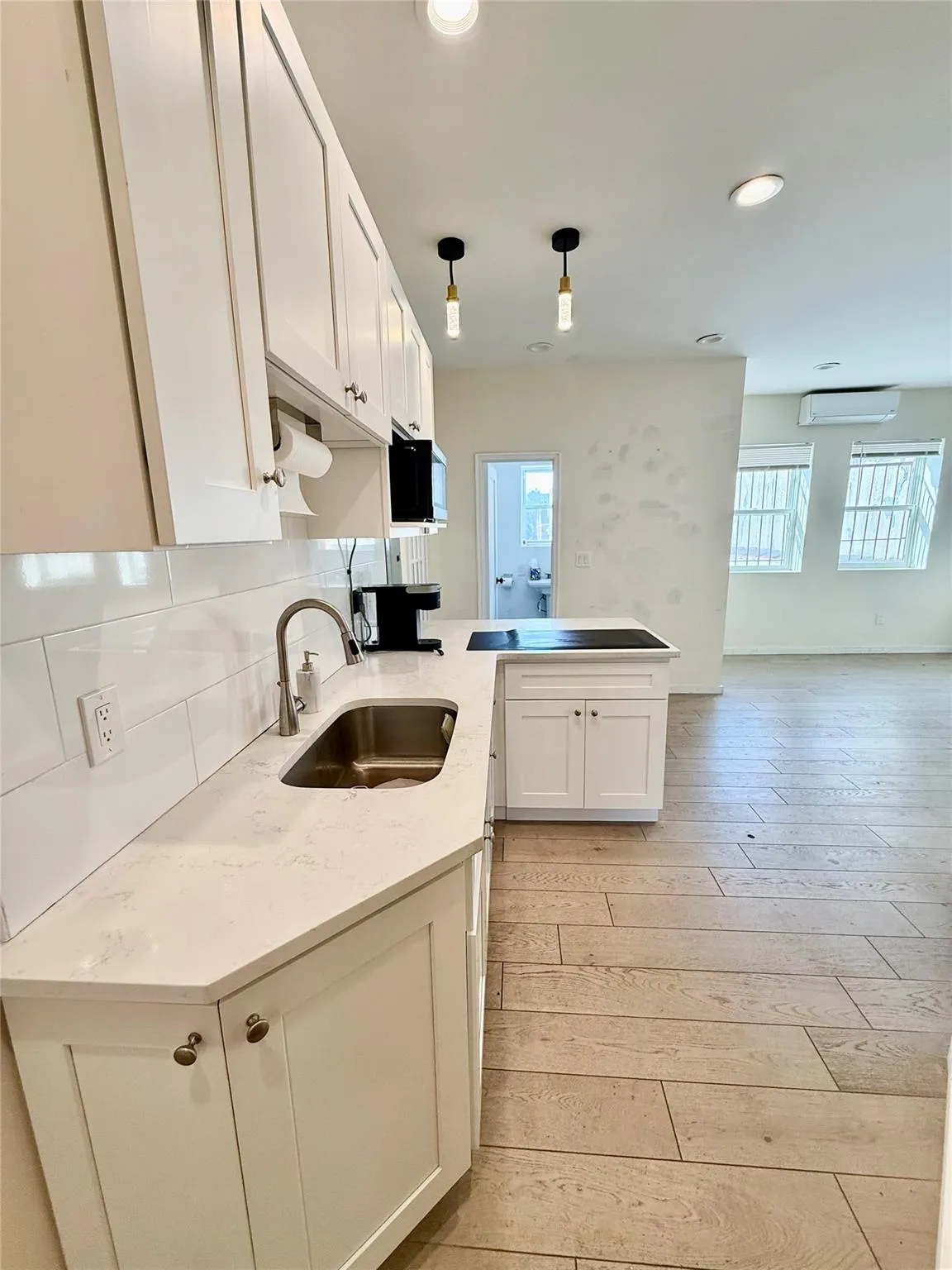 Kitchen featuring a peninsula, white cabinets, light wood-type flooring, open floor plan, and recessed lighting Kitchen featuring a peninsula, white cabinets, light wood-type flooring, open floor plan, and recessed lighting