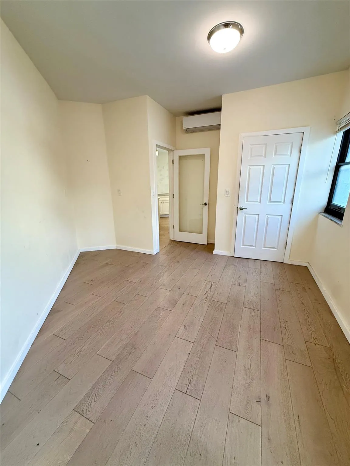 Unfurnished bedroom with wood finished floors and a wall unit AC Unfurnished bedroom with wood finished floors and a wall unit AC