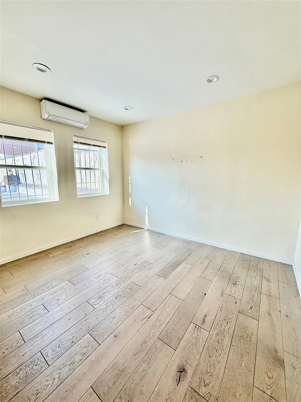 Unfurnished room featuring hardwood / wood-style floors and a wall unit AC Unfurnished room featuring hardwood / wood-style floors and a wall unit AC