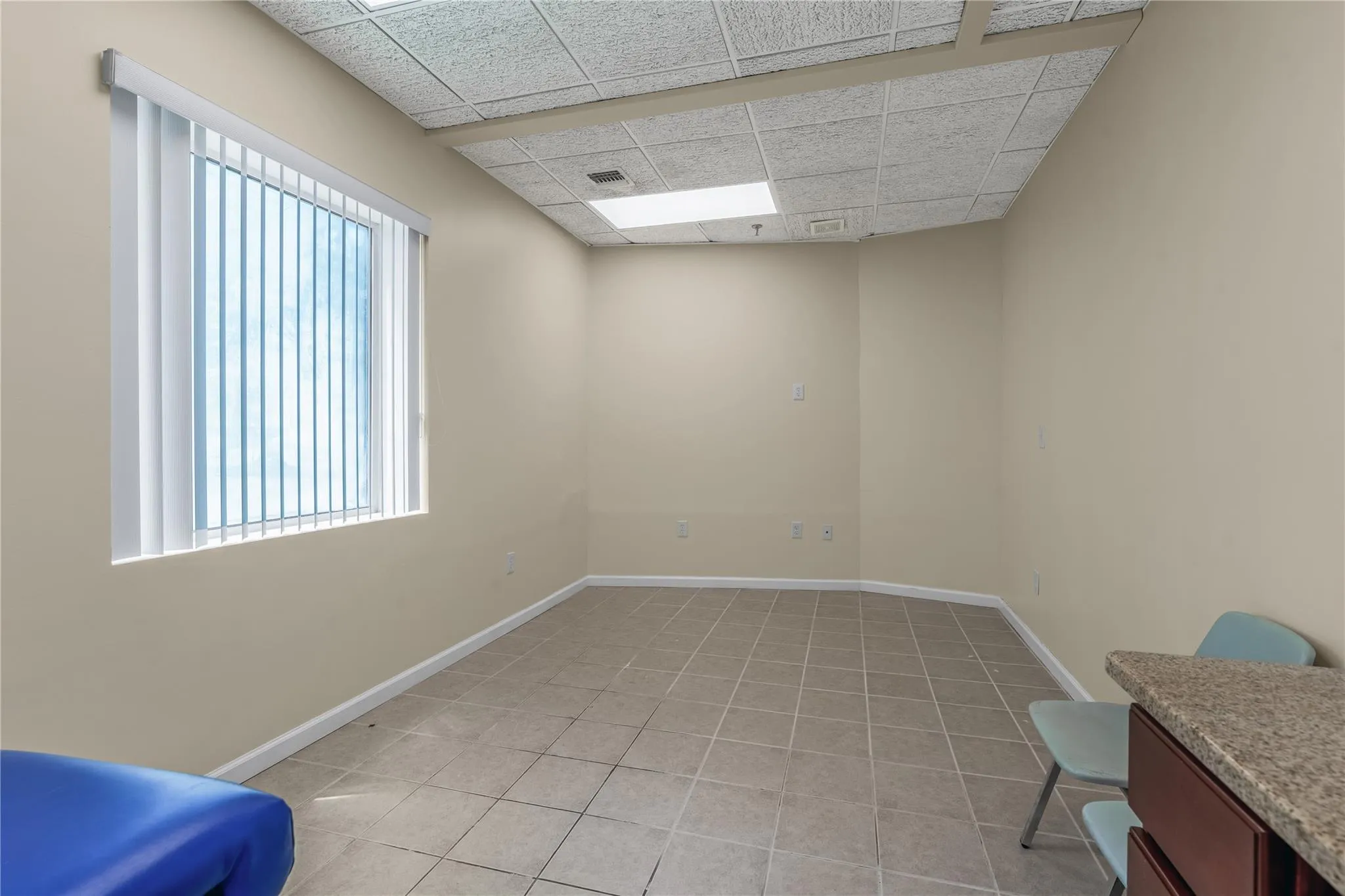 Spare room with a drop ceiling and light tile patterned floors Spare room with a drop ceiling and light tile patterned floors