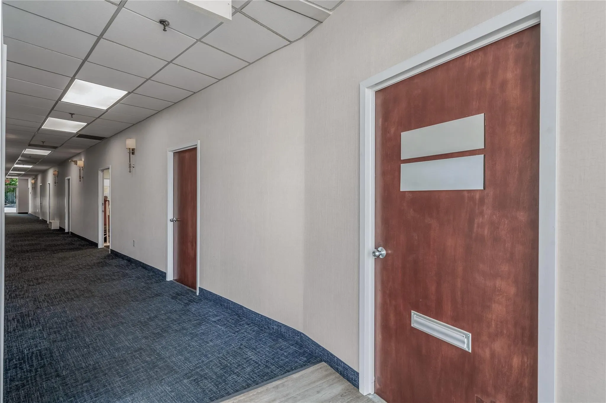 Hallway with carpet flooring and a drop ceiling Hallway with carpet flooring and a drop ceiling