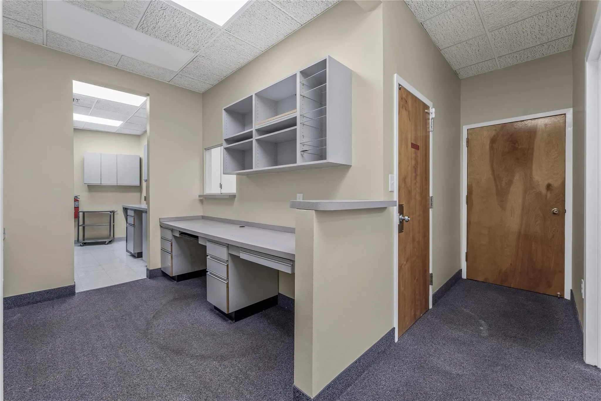 Unfurnished office featuring a drop ceiling, built in study area, and carpet floors Unfurnished office featuring a drop ceiling, built in study area, and carpet floors