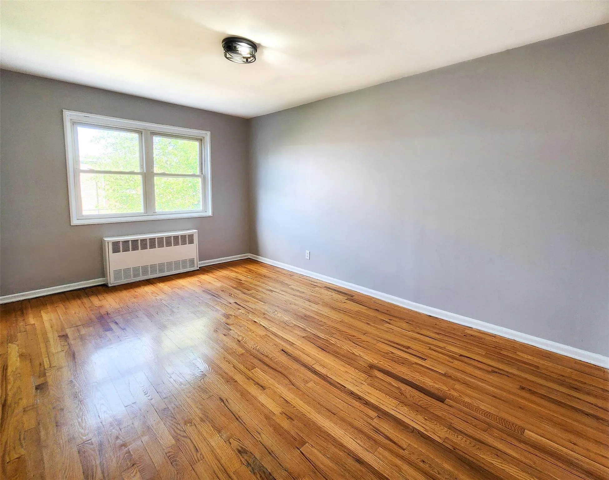 Empty room with radiator heating unit and wood-type flooring Empty room with radiator heating unit and wood-type flooring