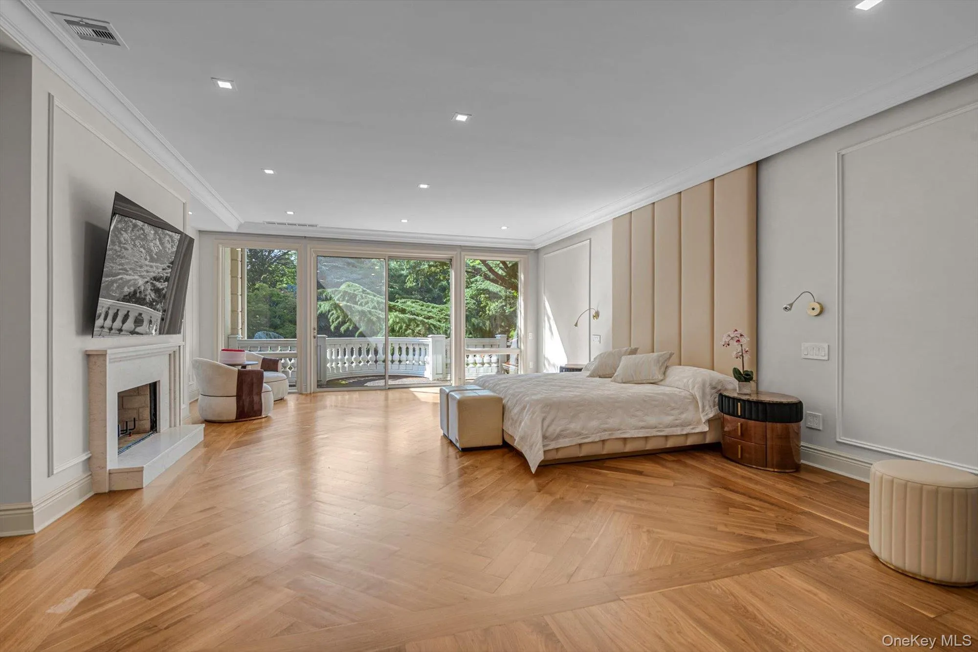 Bedroom featuring access to outside, ornamental molding, a fireplace with raised hearth, a decorative wall, and recessed lighting Bedroom featuring access to outside, ornamental molding, a fireplace with raised hearth, a decorative wall, and recessed lighting