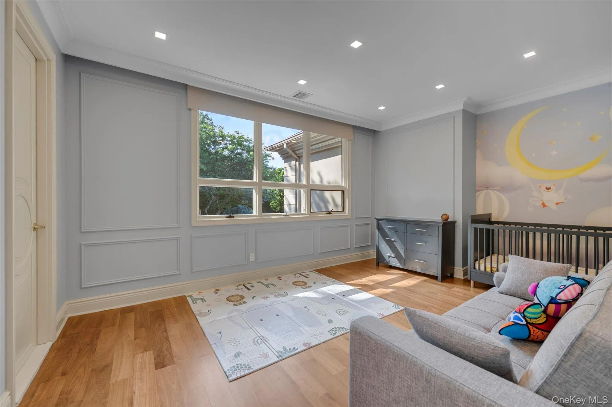Living room with ornamental molding, light wood-style flooring, and a decorative wall Living room with ornamental molding, light wood-style flooring, and a decorative wall