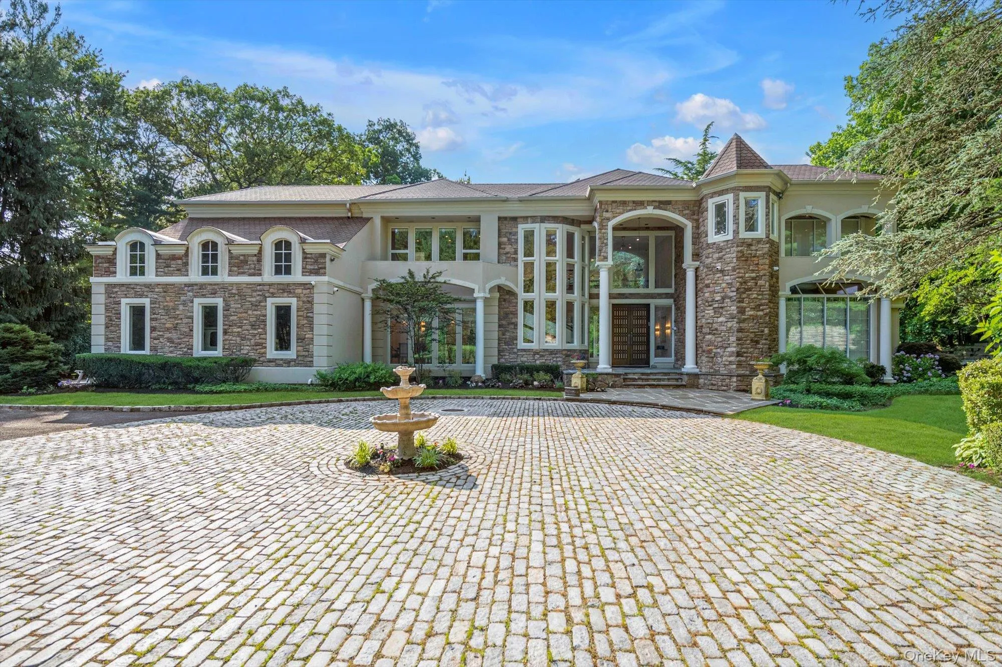 View of front of property with stone siding, curved driveway, and stucco siding View of front of property with stone siding, curved driveway, and stucco siding
