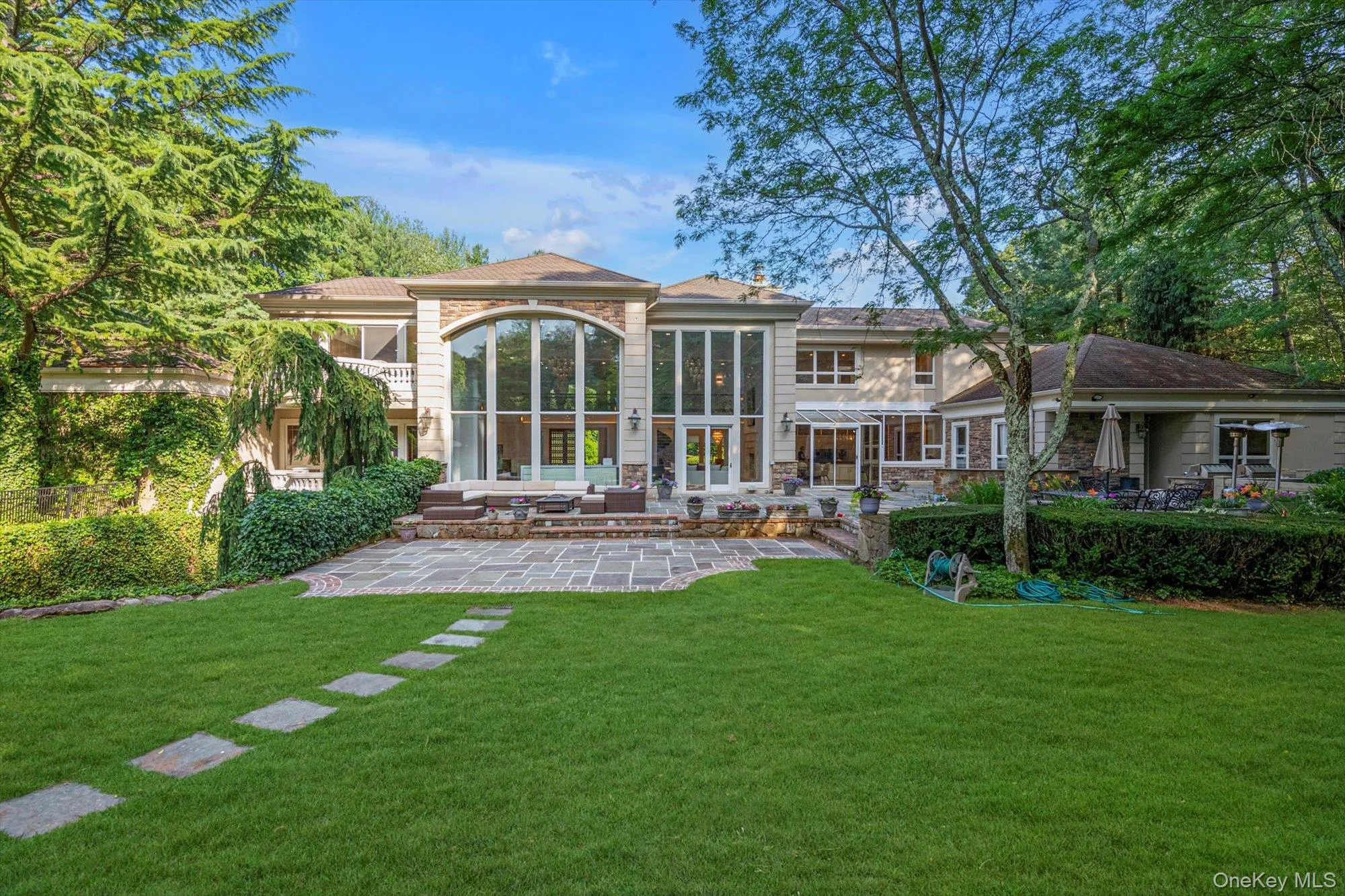 Rear view of property featuring a patio, a yard, and stone siding Rear view of property featuring a patio, a yard, and stone siding