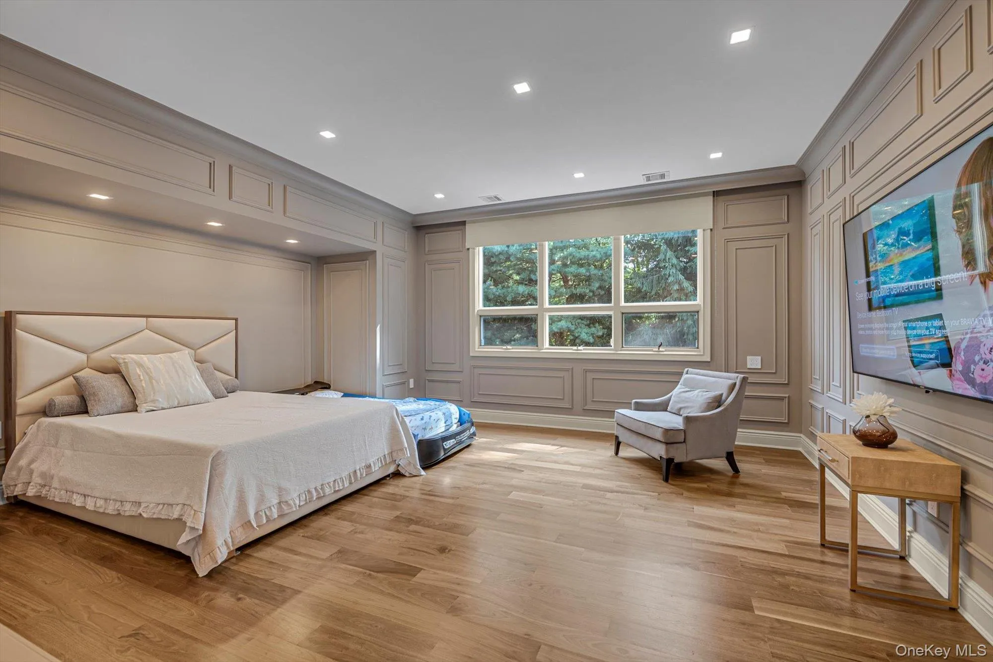 Bedroom with a decorative wall, ornamental molding, light wood finished floors, and recessed lighting Bedroom with a decorative wall, ornamental molding, light wood finished floors, and recessed lighting
