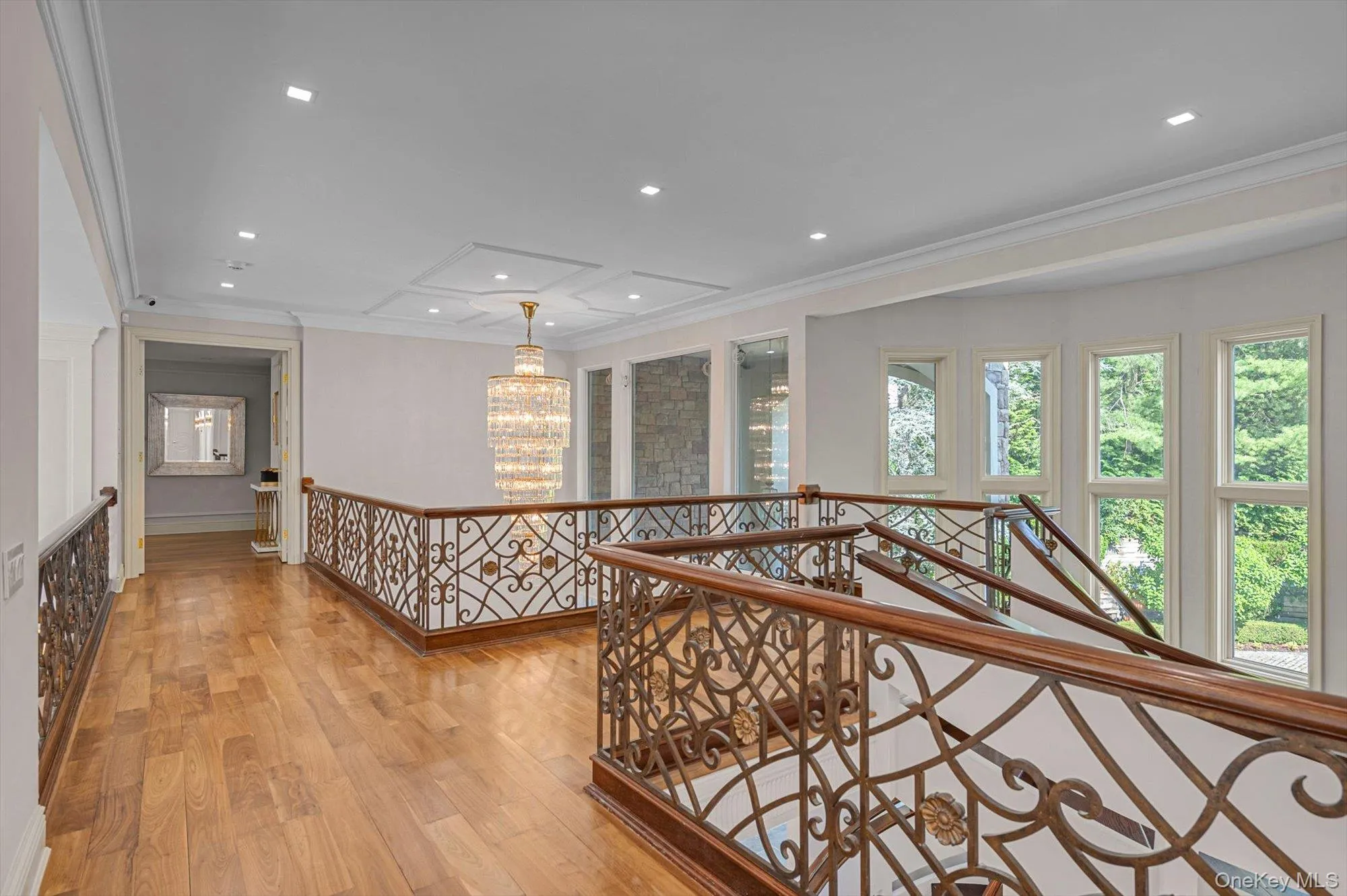 Hallway with an upstairs landing, ornamental molding, light wood-style floors, recessed lighting, and a chandelier Hallway with an upstairs landing, ornamental molding, light wood-style floors, recessed lighting, and a chandelier