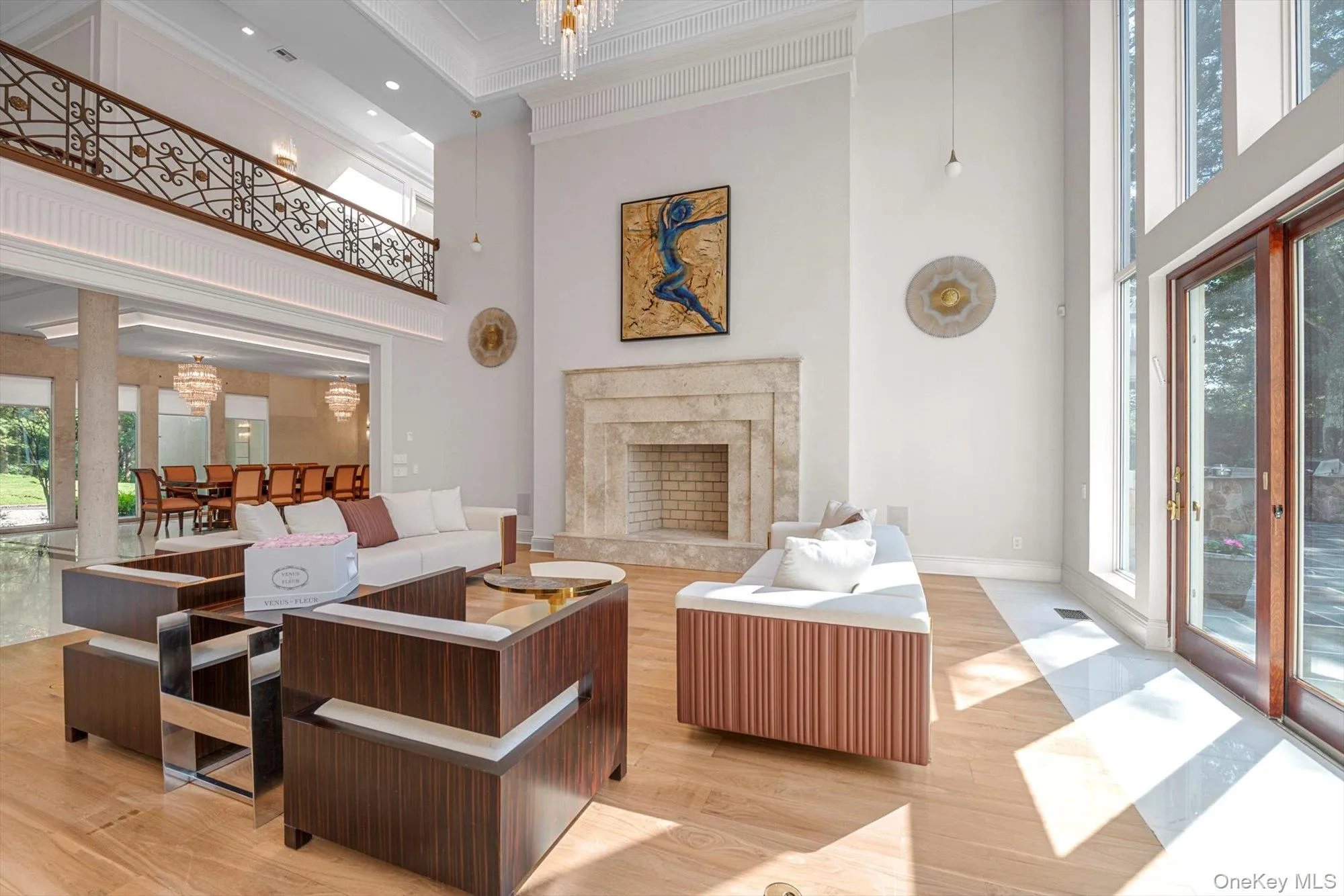 Living area featuring ornamental molding, a high ceiling, plenty of natural light, a high end fireplace, and a chandelier Living area featuring ornamental molding, a high ceiling, plenty of natural light, a high end fireplace, and a chandelier