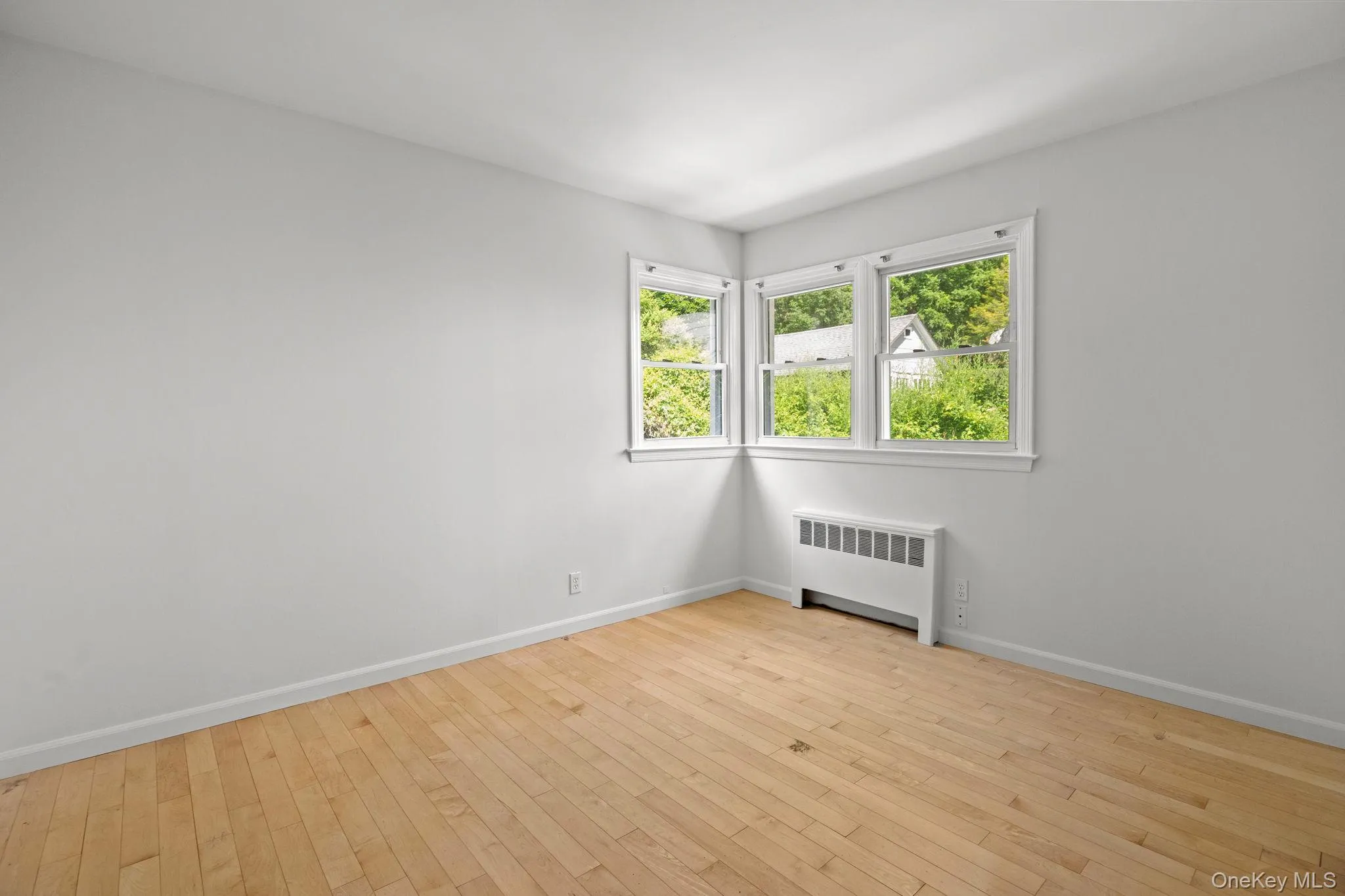 Unfurnished room with radiator heating unit and hardwood / wood-style floors Unfurnished room with radiator heating unit and hardwood / wood-style floors