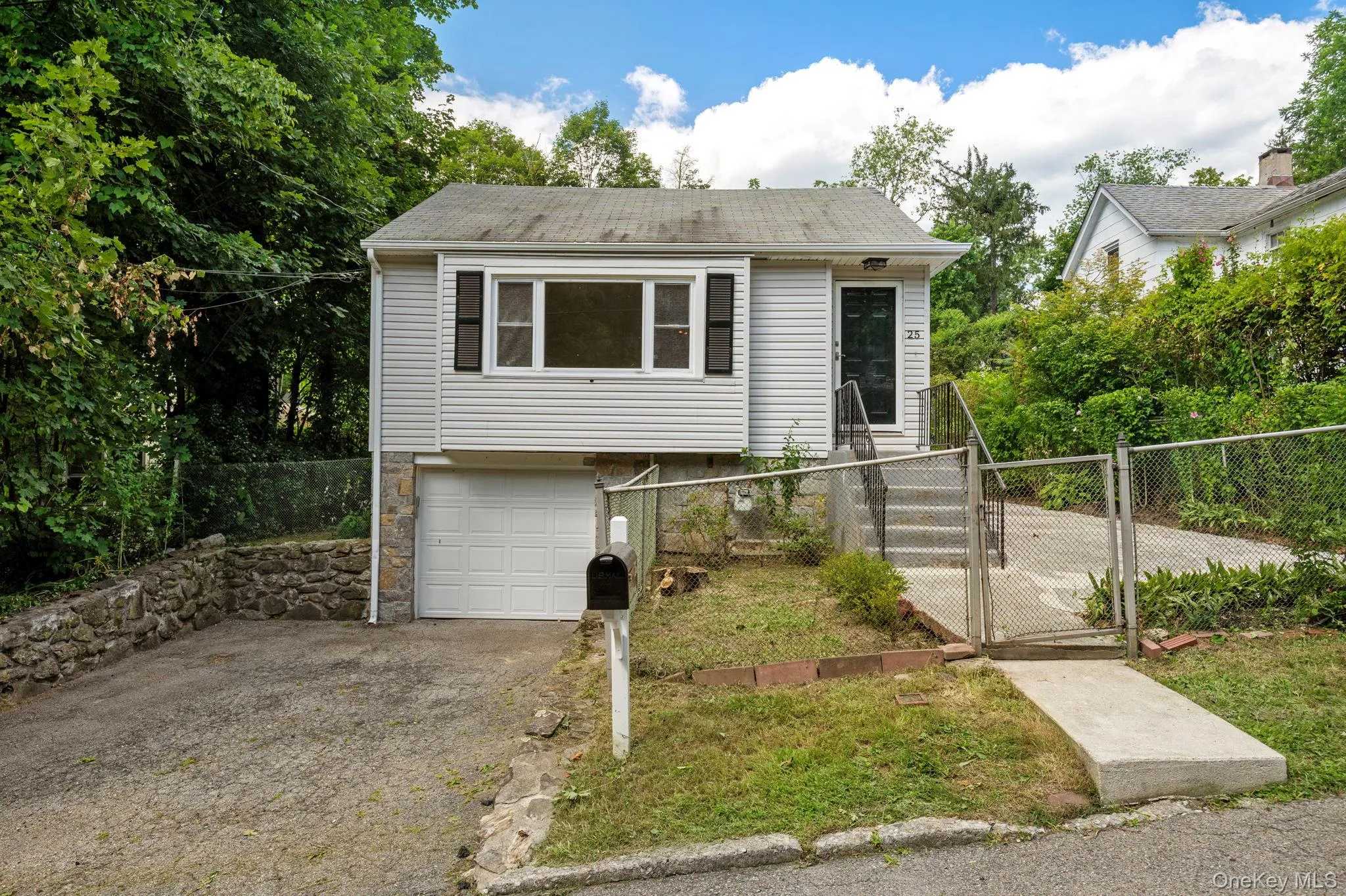 View of front of house featuring a gate, an attached garage, asphalt driveway, stone siding, and view of wooded area View of front of house featuring a gate, an attached garage, asphalt driveway, stone siding, and view of wooded area
