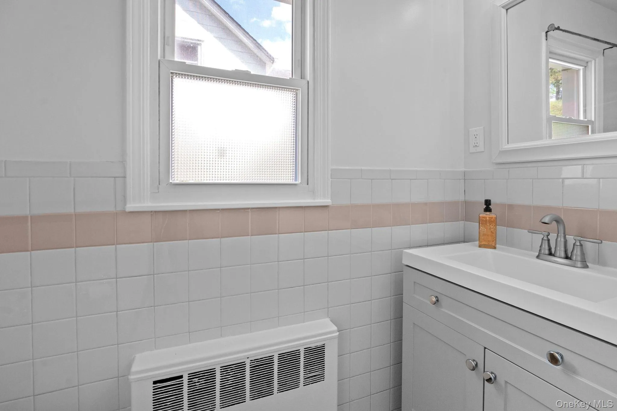 Bathroom featuring vanity, radiator heating unit, tile walls, and a wainscoted wall Bathroom featuring vanity, radiator heating unit, tile walls, and a wainscoted wall