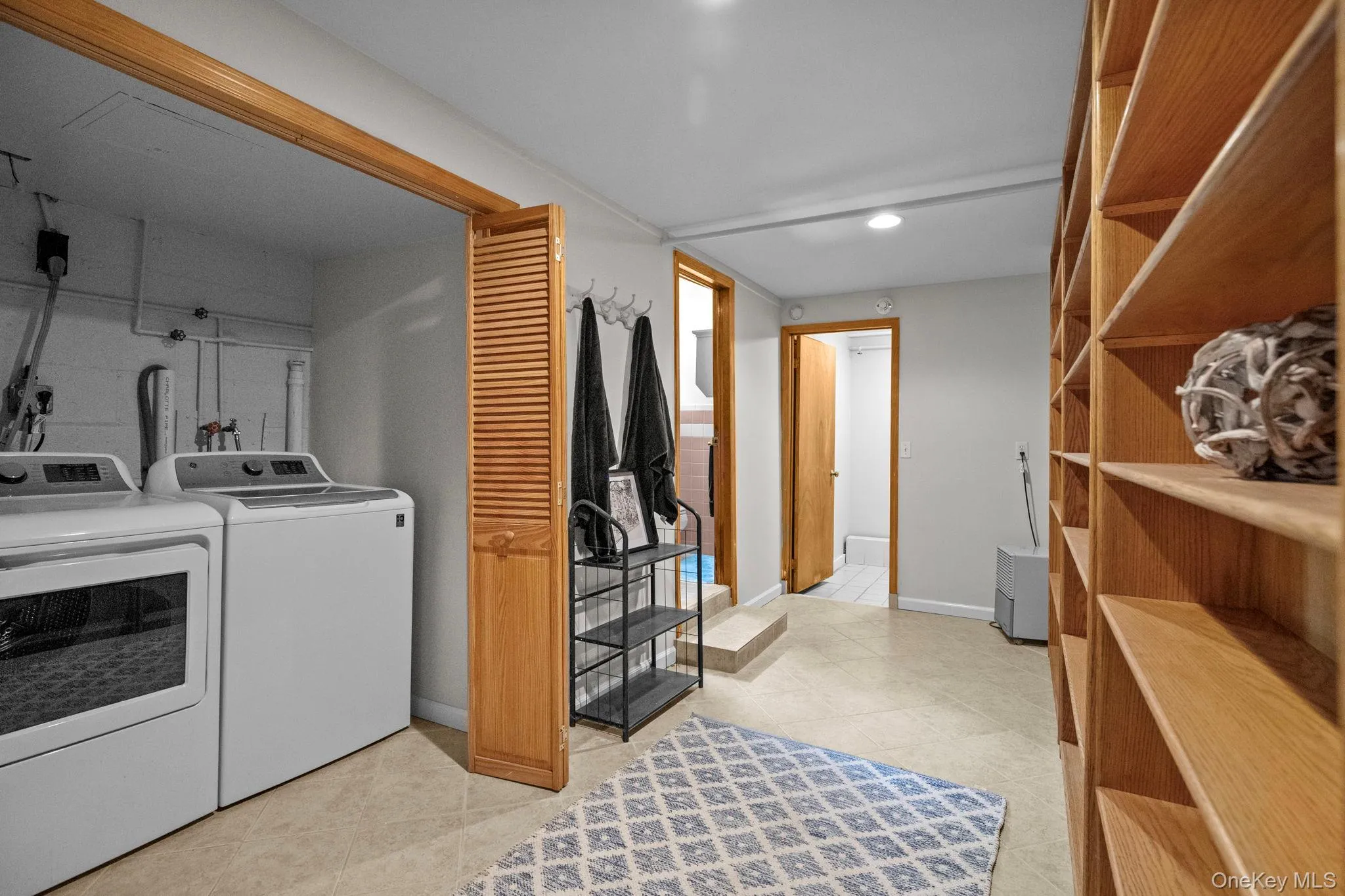 Laundry area with separate washer and dryer and light tile patterned flooring Laundry area with separate washer and dryer and light tile patterned flooring