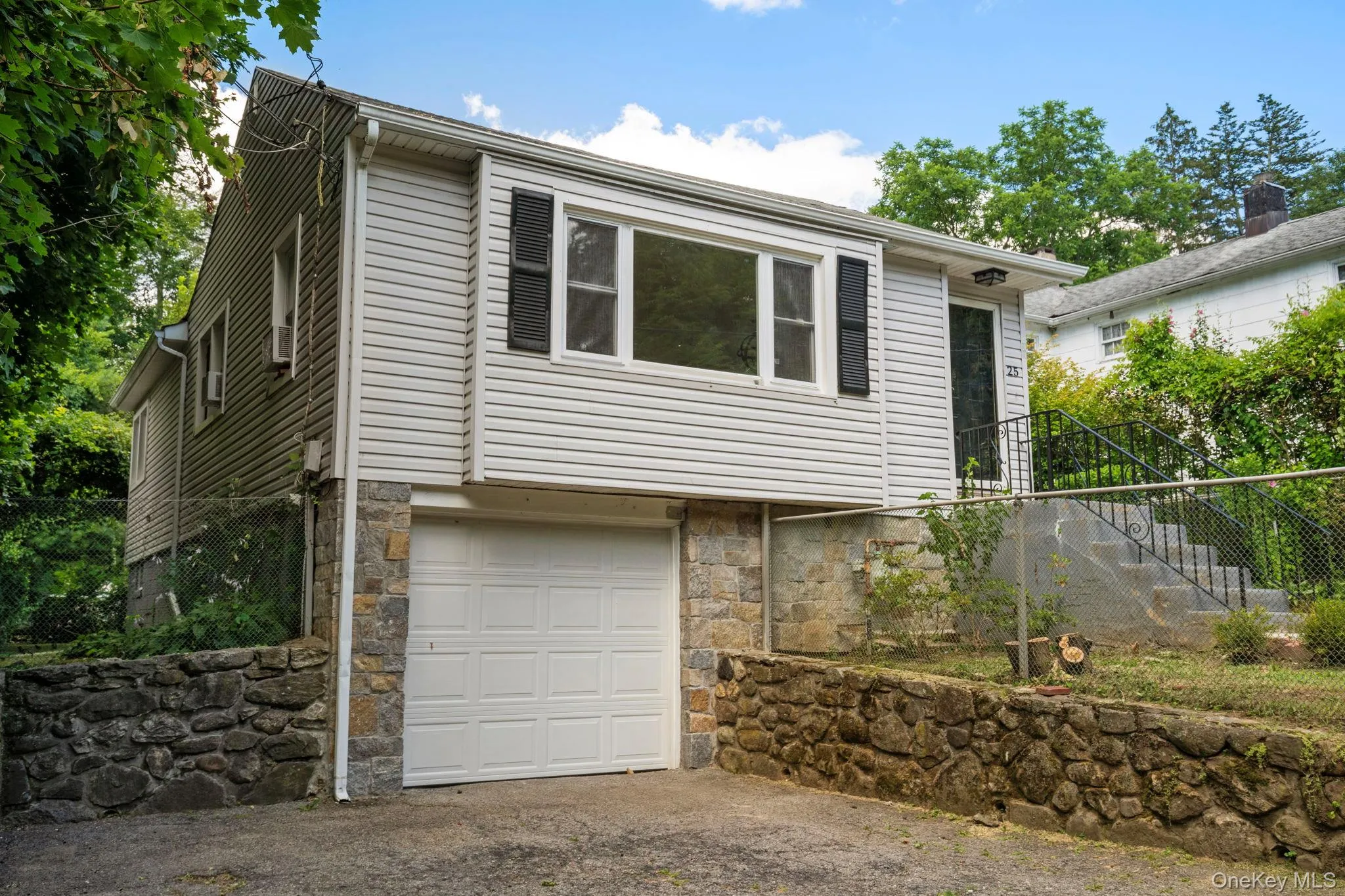 View of front of property featuring stone siding, an attached garage, stairway, and driveway View of front of property featuring stone siding, an attached garage, stairway, and driveway