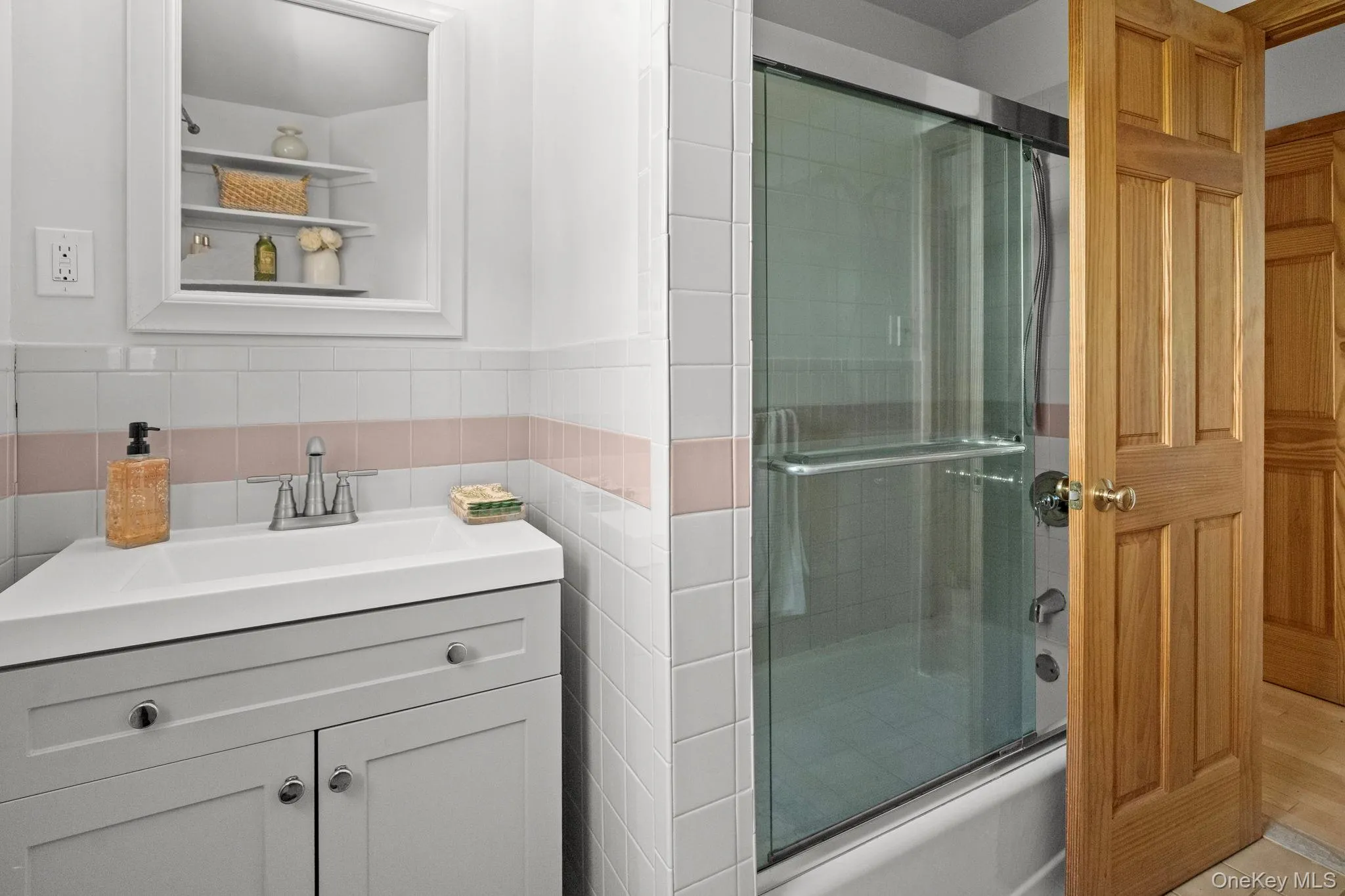 Full bath with vanity, enclosed tub / shower combo, tile walls, and a wainscoted wall Full bath with vanity, enclosed tub / shower combo, tile walls, and a wainscoted wall