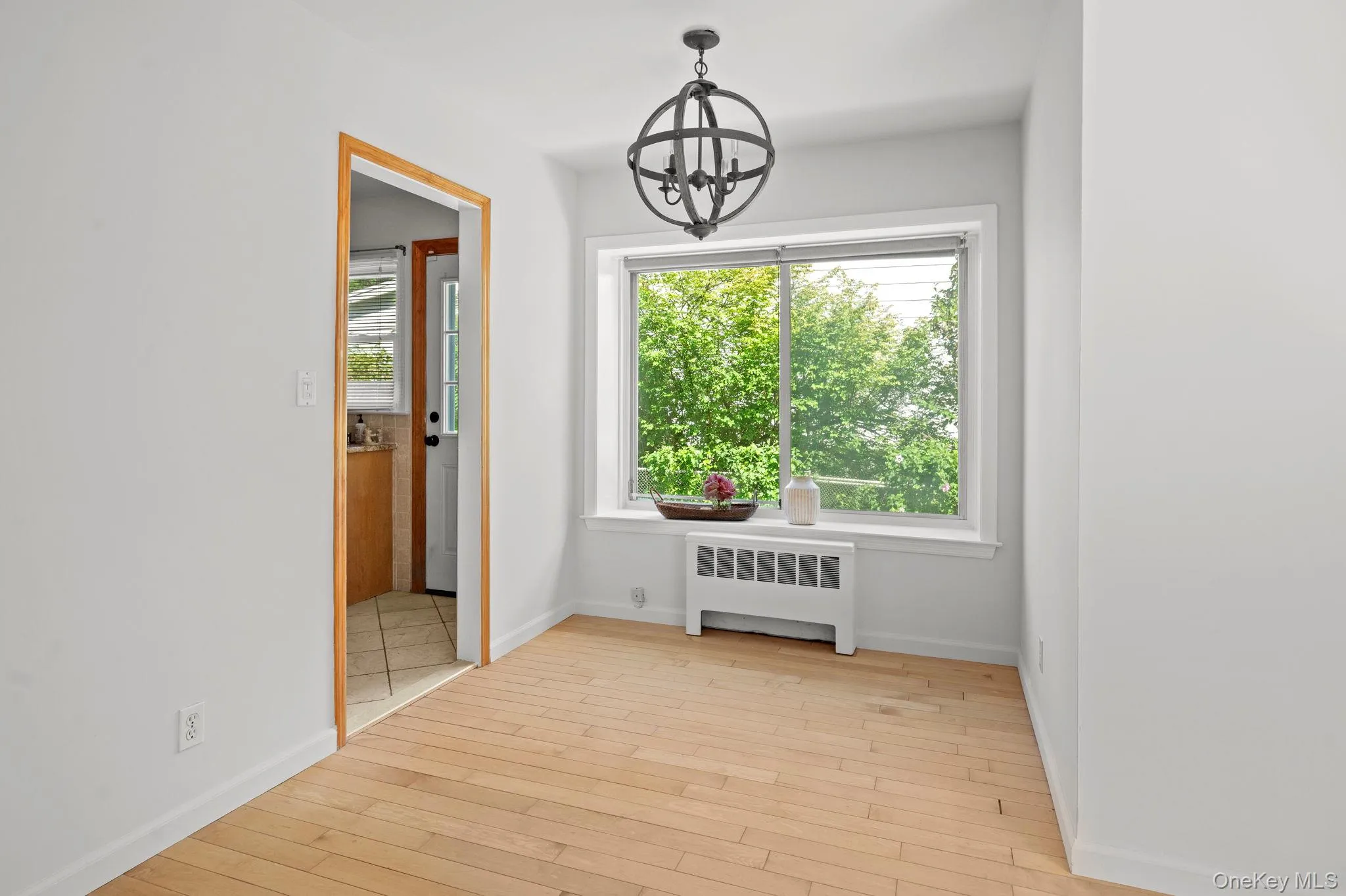 Unfurnished dining area with a chandelier, radiator heating unit, light wood-type flooring, and plenty of natural light Unfurnished dining area with a chandelier, radiator heating unit, light wood-type flooring, and plenty of natural light