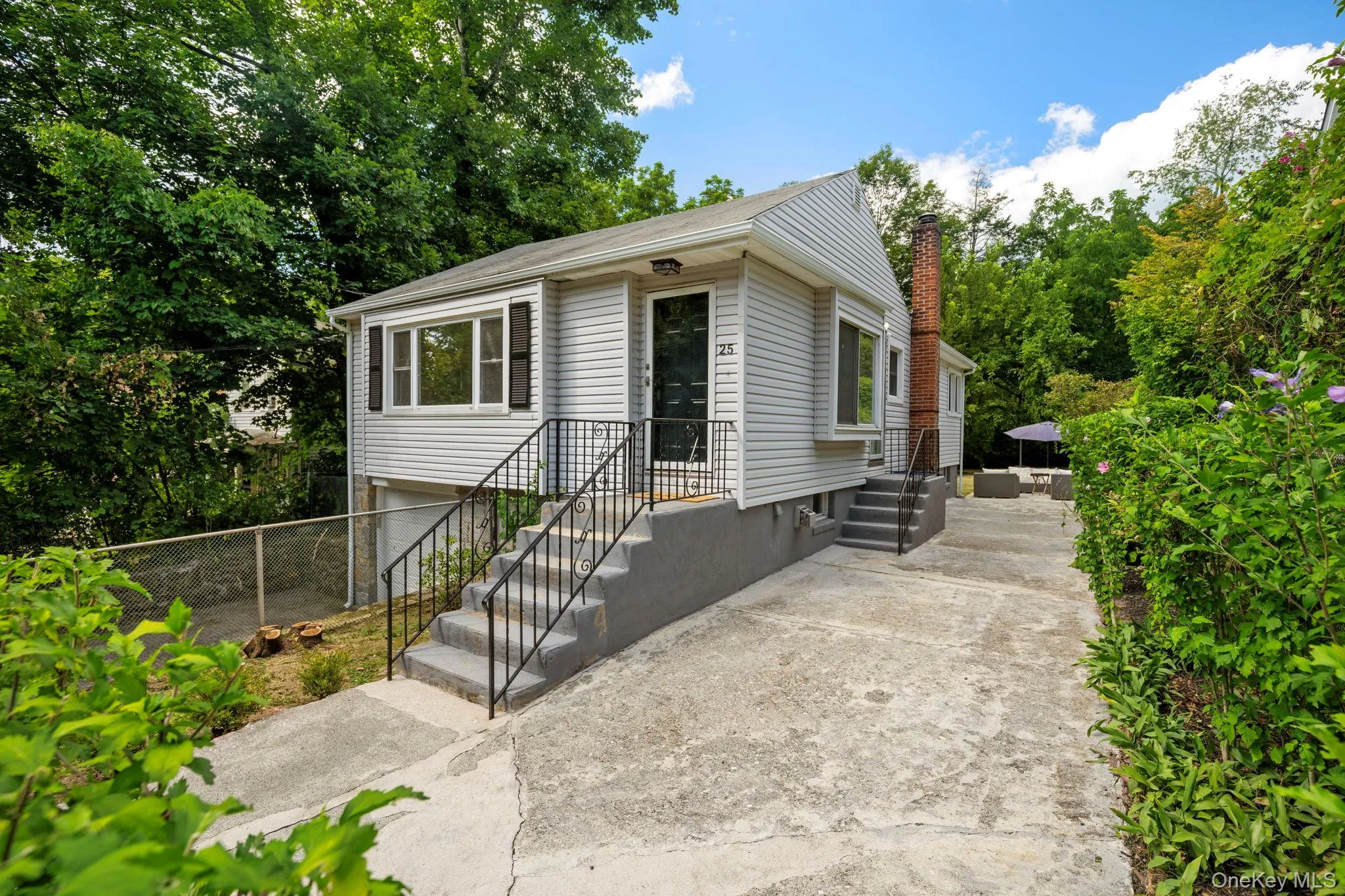 View of front facade featuring a chimney and view of wooded area View of front facade featuring a chimney and view of wooded area