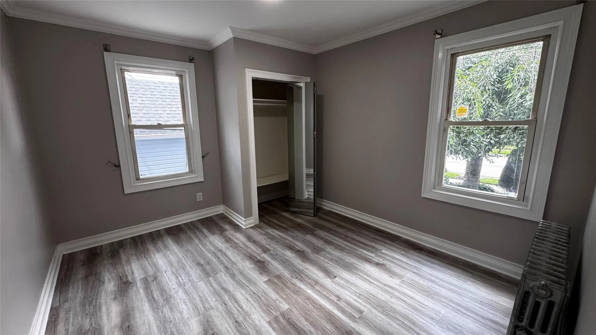 Unfurnished bedroom with ornamental molding, light wood-style floors, and a closet Unfurnished bedroom with ornamental molding, light wood-style floors, and a closet