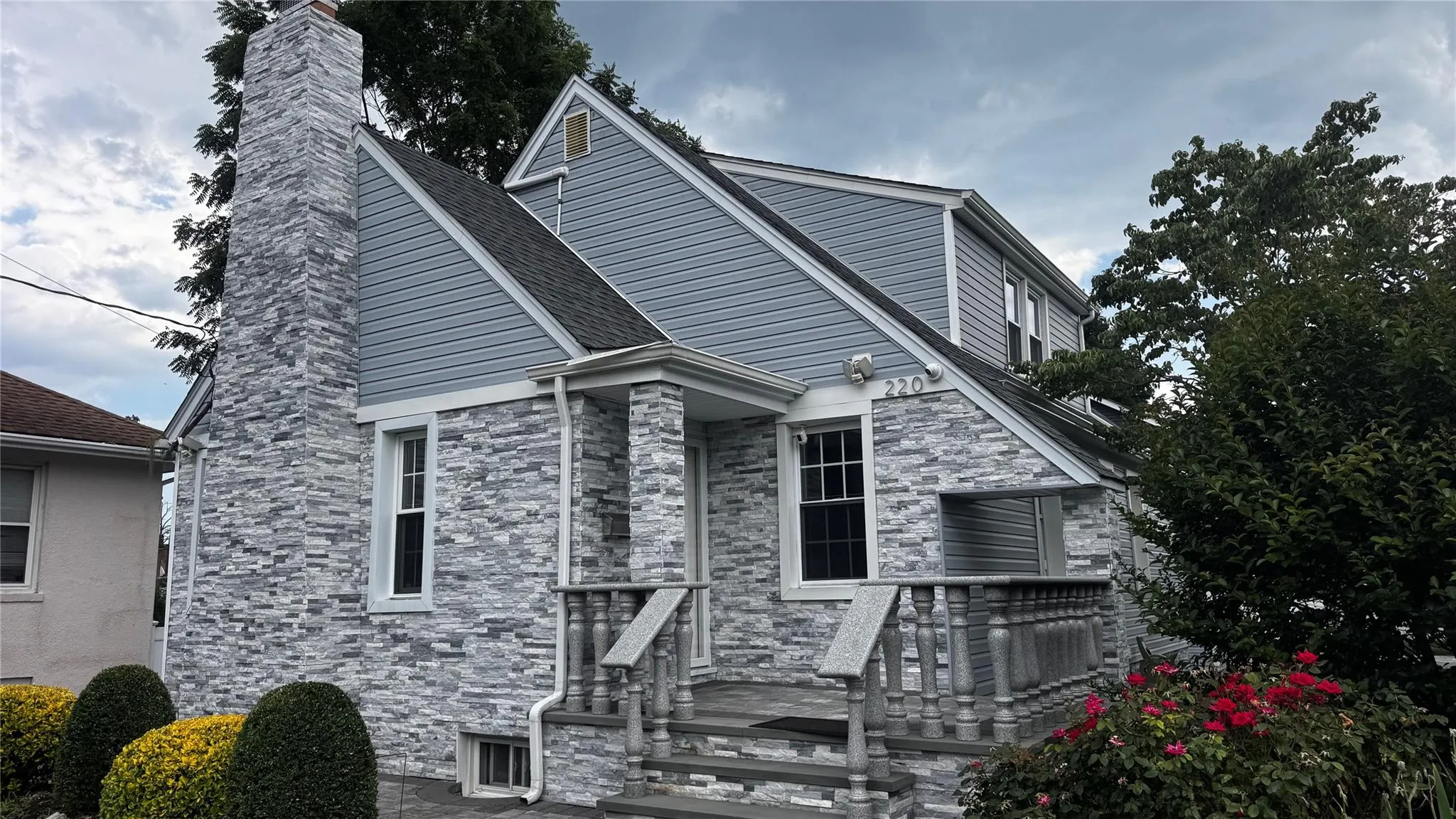 View of front of house with stone siding, a chimney, and roof with shingles View of front of house with stone siding, a chimney, and roof with shingles