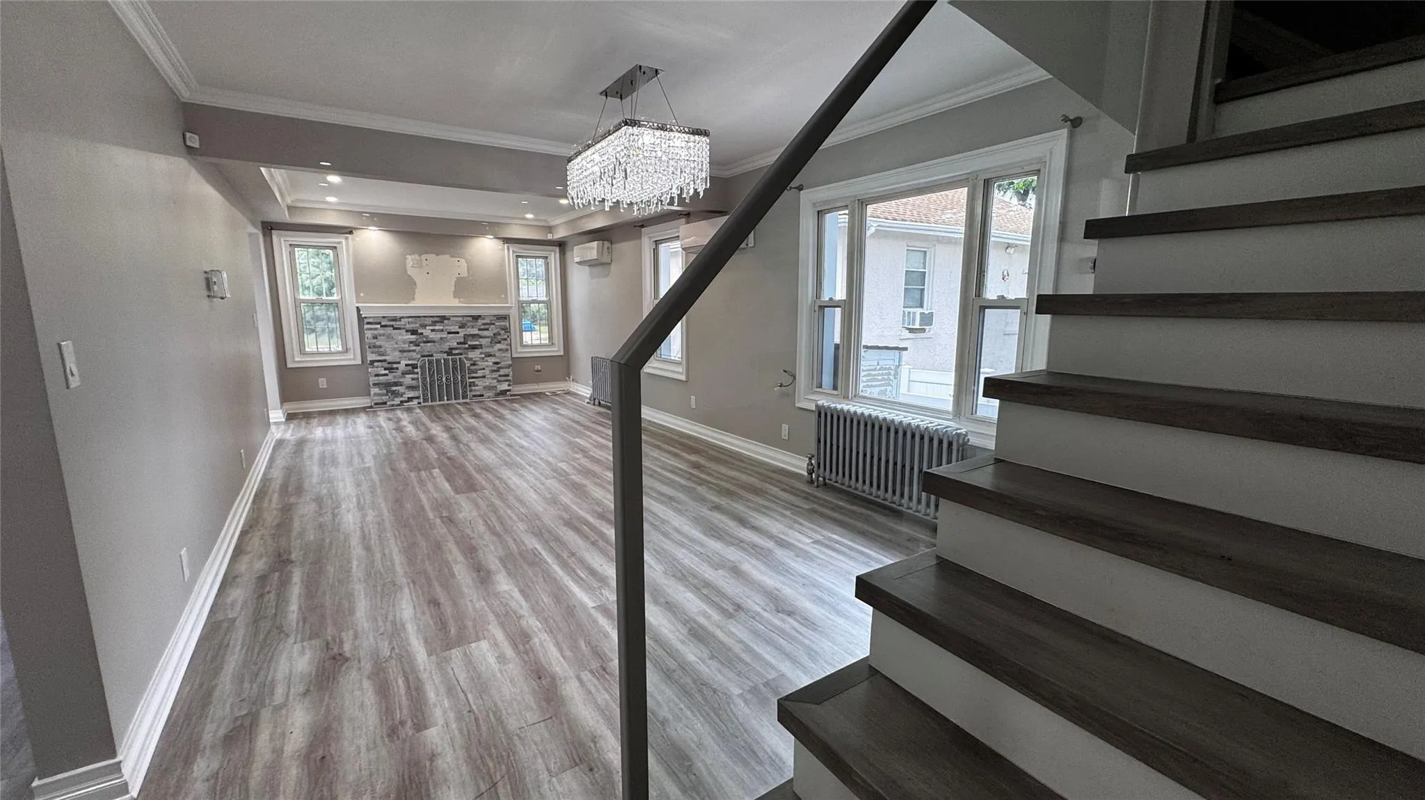 Stairs with wood finished floors, radiator, crown molding, and a chandelier Stairs with wood finished floors, radiator, crown molding, and a chandelier