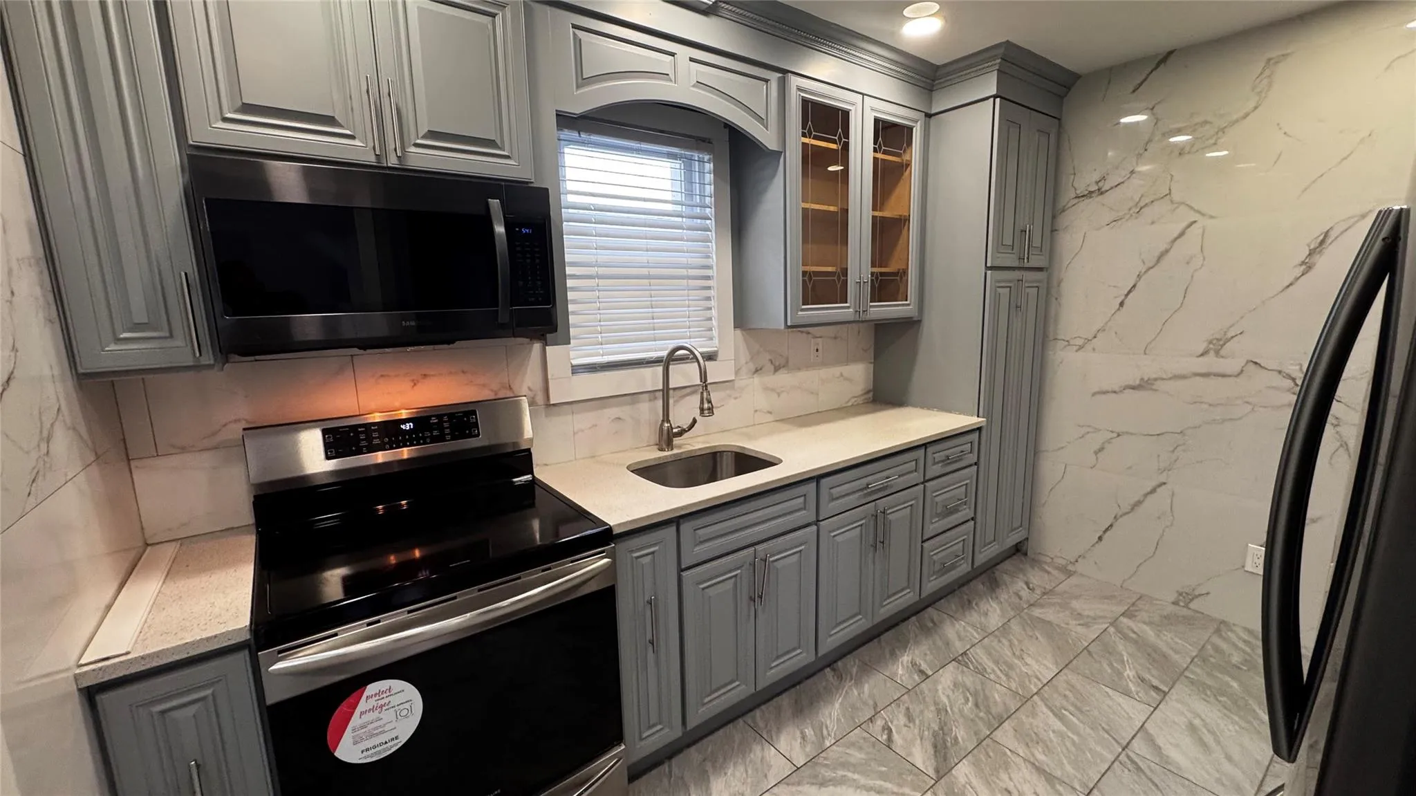 Kitchen with gray cabinets, electric range, freestanding refrigerator, glass insert cabinets, and recessed lighting Kitchen with gray cabinets, electric range, freestanding refrigerator, glass insert cabinets, and recessed lighting
