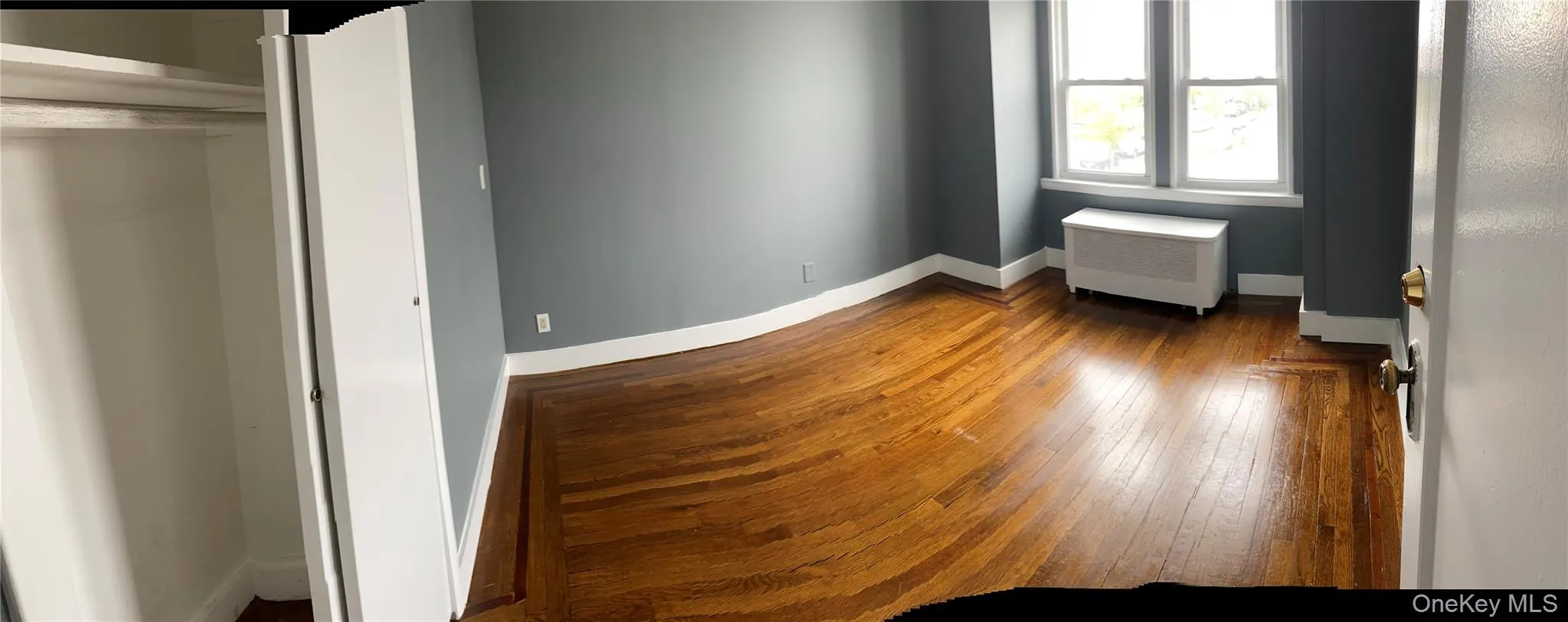 Unfurnished bedroom featuring radiator and hardwood / wood-style flooring Unfurnished bedroom featuring radiator and hardwood / wood-style flooring