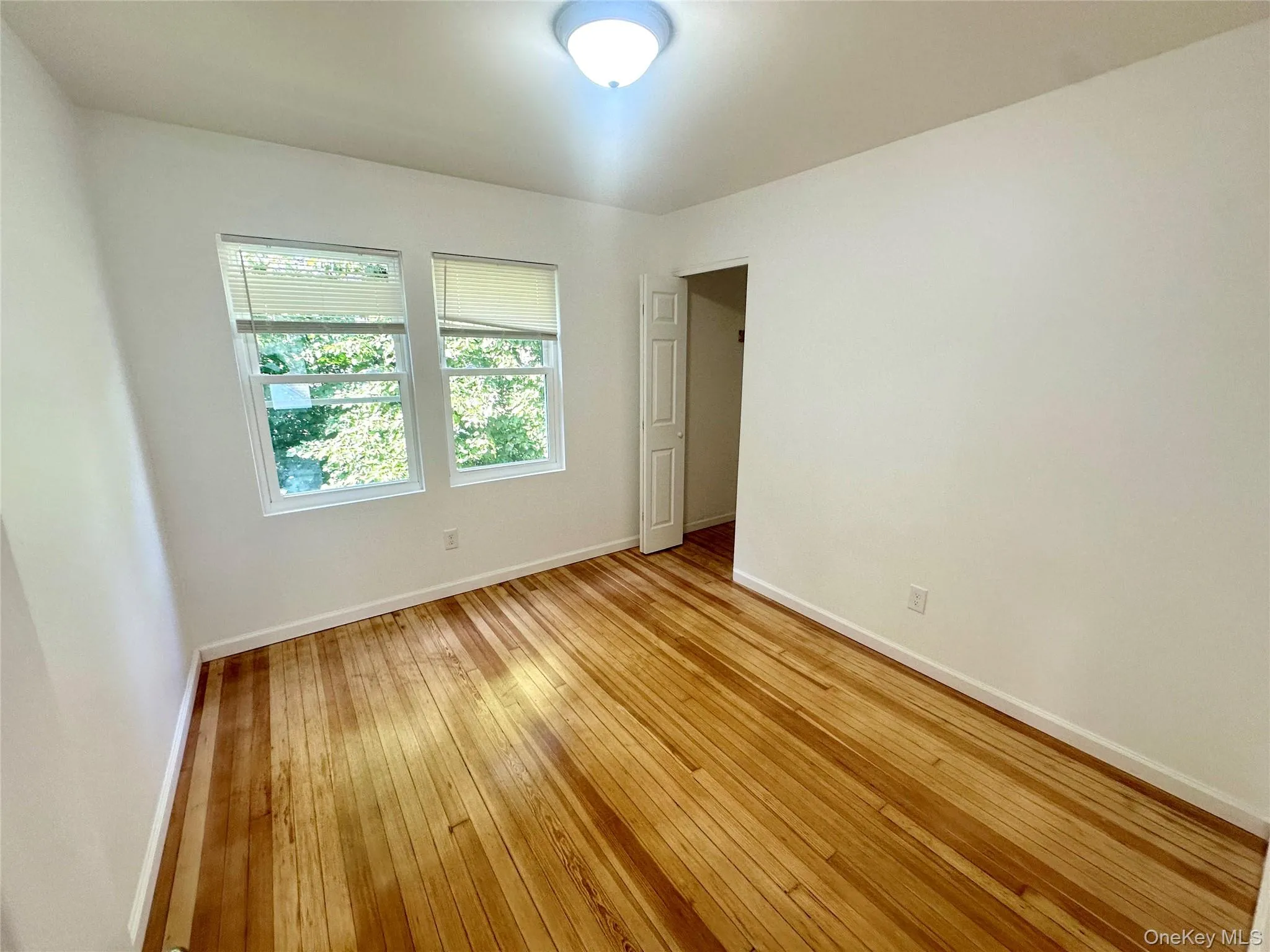 Unfurnished room with light wood finished floors and baseboards Unfurnished room with light wood finished floors and baseboards