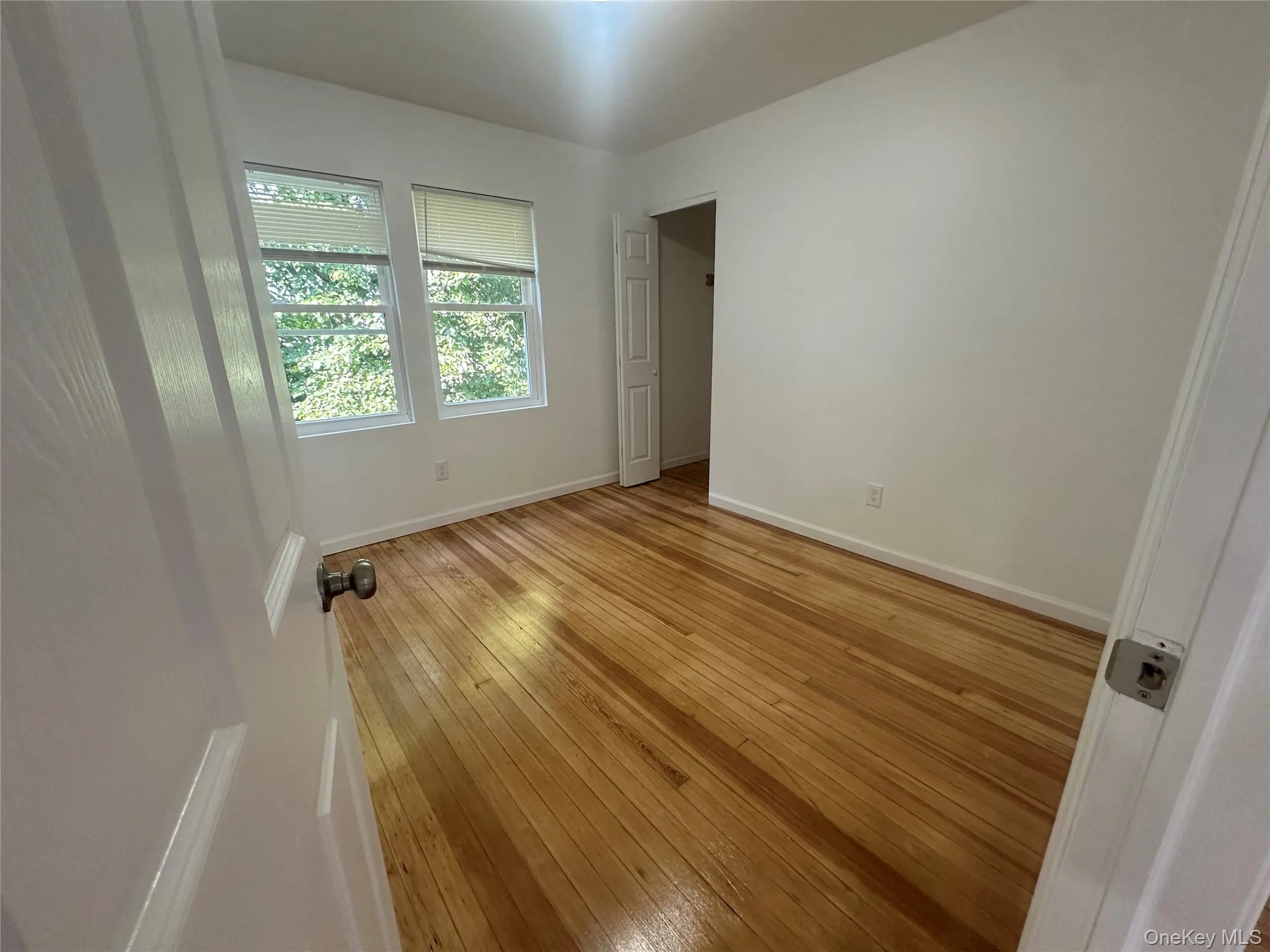 Unfurnished bedroom with light wood finished floors and baseboards Unfurnished bedroom with light wood finished floors and baseboards