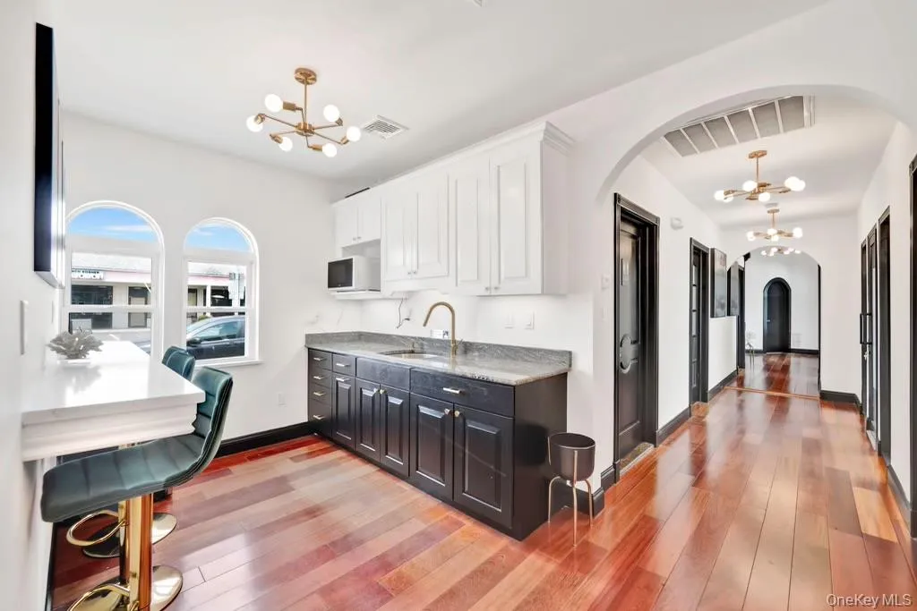 Kitchen featuring a chandelier, arched walkways, white cabinetry, and light wood-style floors Kitchen featuring a chandelier, arched walkways, white cabinetry, and light wood-style floors