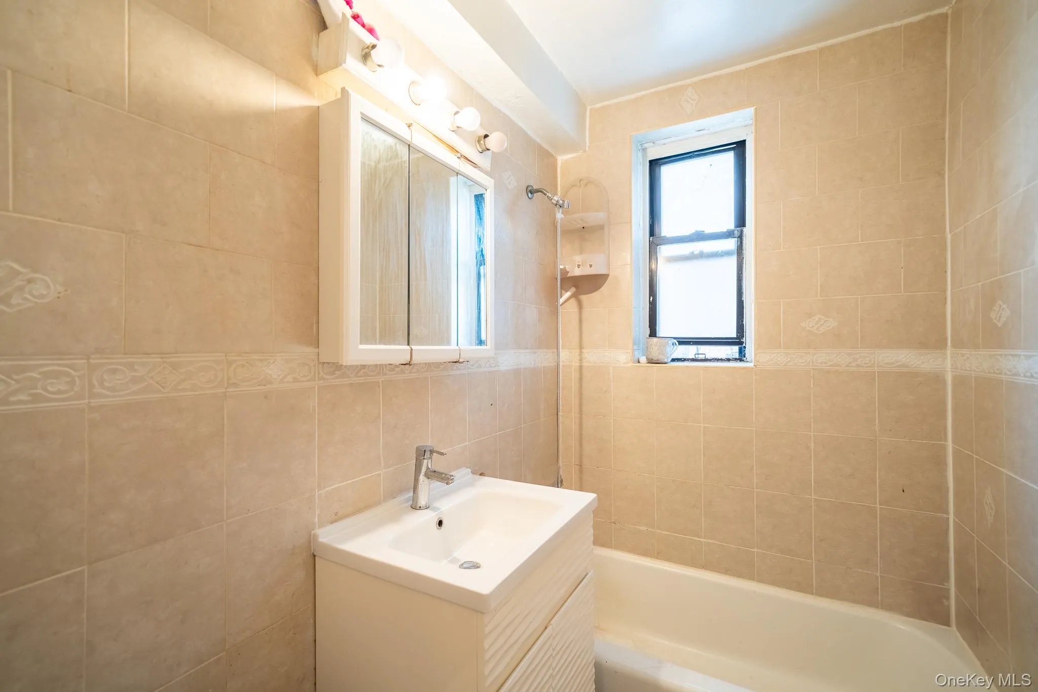 Bathroom featuring tile walls, vanity, and shower / bathtub combination Bathroom featuring tile walls, vanity, and shower / bathtub combination
