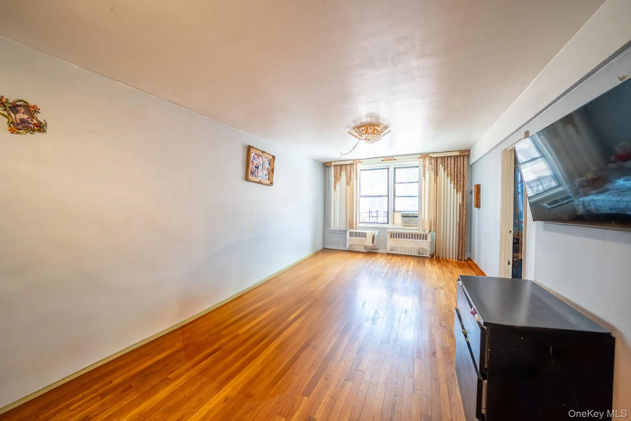 Unfurnished living room featuring hardwood / wood-style floors and radiator Unfurnished living room featuring hardwood / wood-style floors and radiator