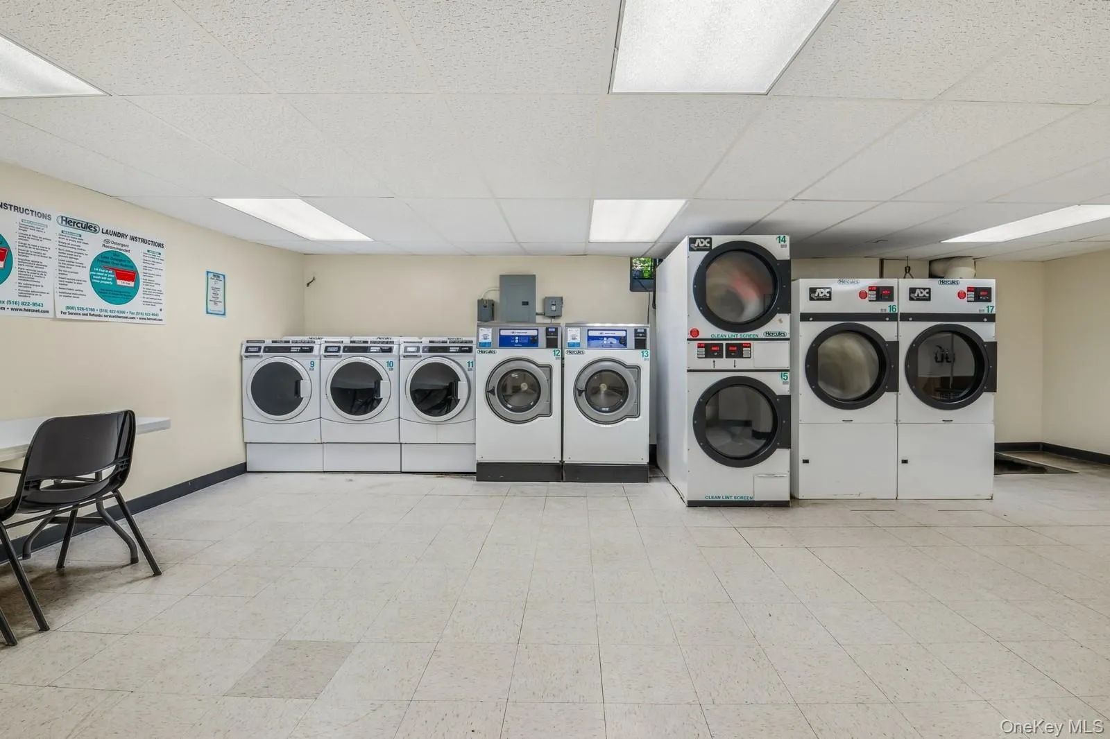 Communal laundry room featuring washer and clothes dryer, estacked washer and dryer, light floors, and electric panel Communal laundry room featuring washer and clothes dryer, estacked washer and dryer, light floors, and electric panel