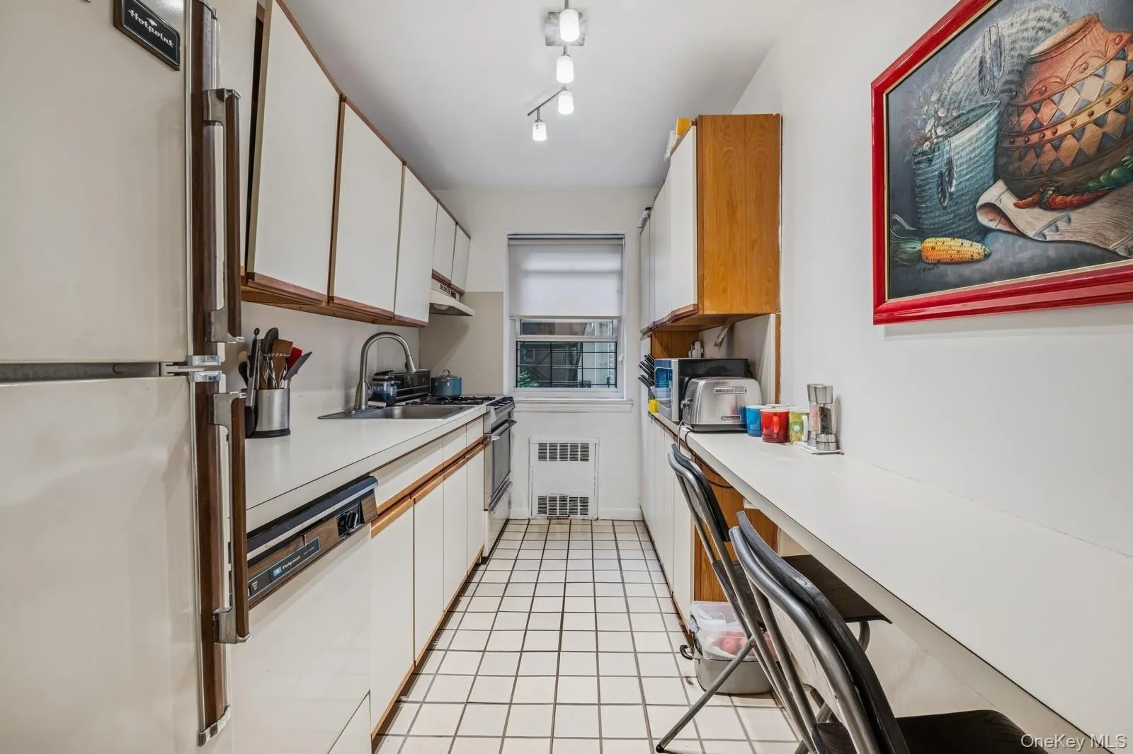 Kitchen featuring freestanding refrigerator, light countertops, white dishwasher, and white cabinets Kitchen featuring freestanding refrigerator, light countertops, white dishwasher, and white cabinets