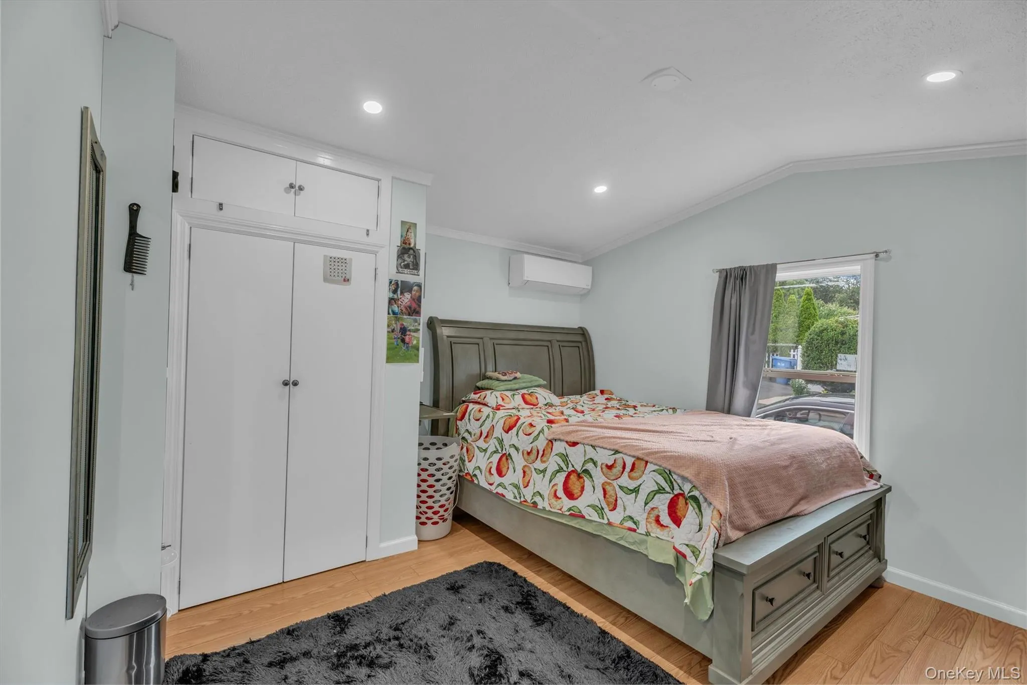 Bedroom with ornamental molding, light wood-style floors, vaulted ceiling, recessed lighting, and a wall mounted AC Bedroom with ornamental molding, light wood-style floors, vaulted ceiling, recessed lighting, and a wall mounted AC