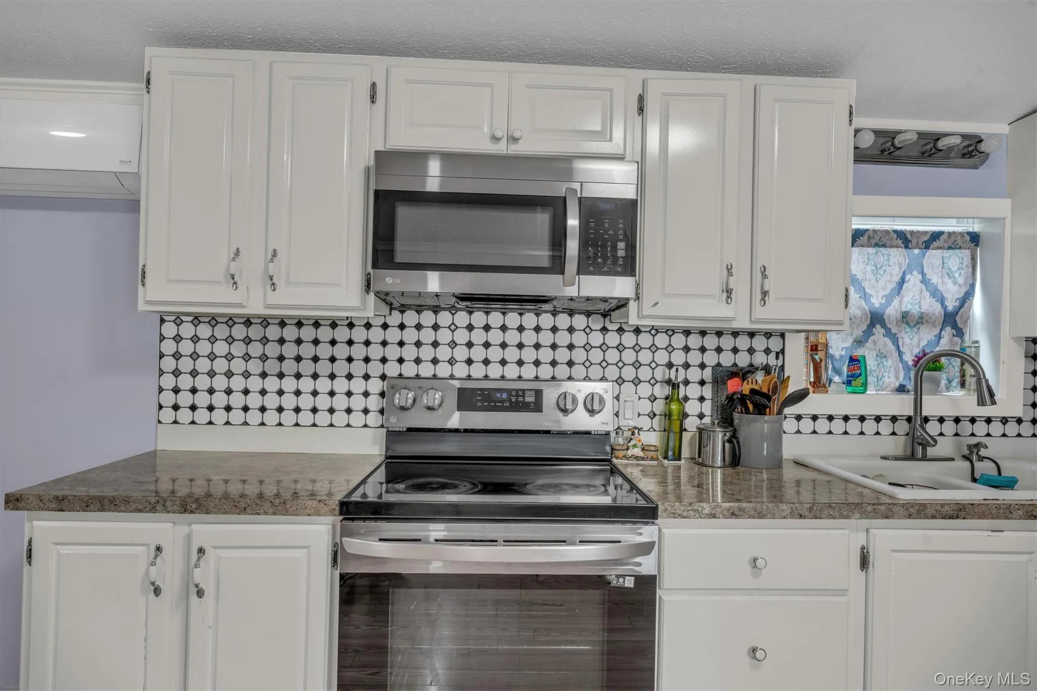 Kitchen with stainless steel appliances, white cabinetry, and backsplash Kitchen with stainless steel appliances, white cabinetry, and backsplash