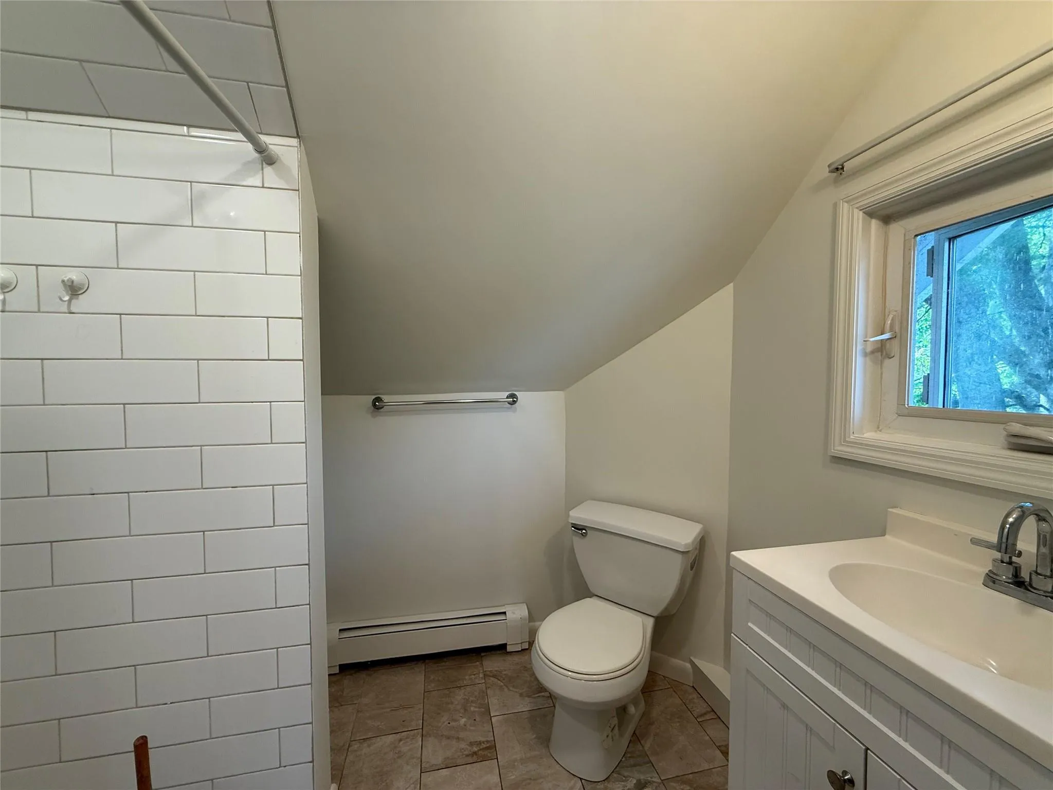 Full bath featuring vaulted ceiling, a baseboard radiator, vanity, and tiled shower Full bath featuring vaulted ceiling, a baseboard radiator, vanity, and tiled shower