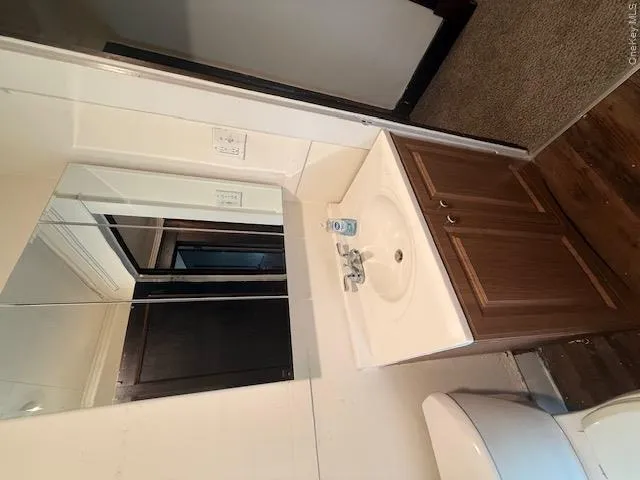 Bathroom vanity with wood-finish cabinetry, white countertop and integrated sink, and a tri-fold mirrored medicine cabinet Bathroom vanity with wood-finish cabinetry, white countertop and integrated sink, and a tri-fold mirrored medicine cabinet