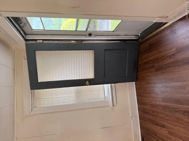 Entryway featuring wood-finish flooring, a storm door with screen, and a window with blinds Entryway featuring wood-finish flooring, a storm door with screen, and a window with blinds