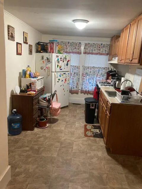 Kitchen with freestanding refrigerator, crown molding, light countertops, and range hood Kitchen with freestanding refrigerator, crown molding, light countertops, and range hood