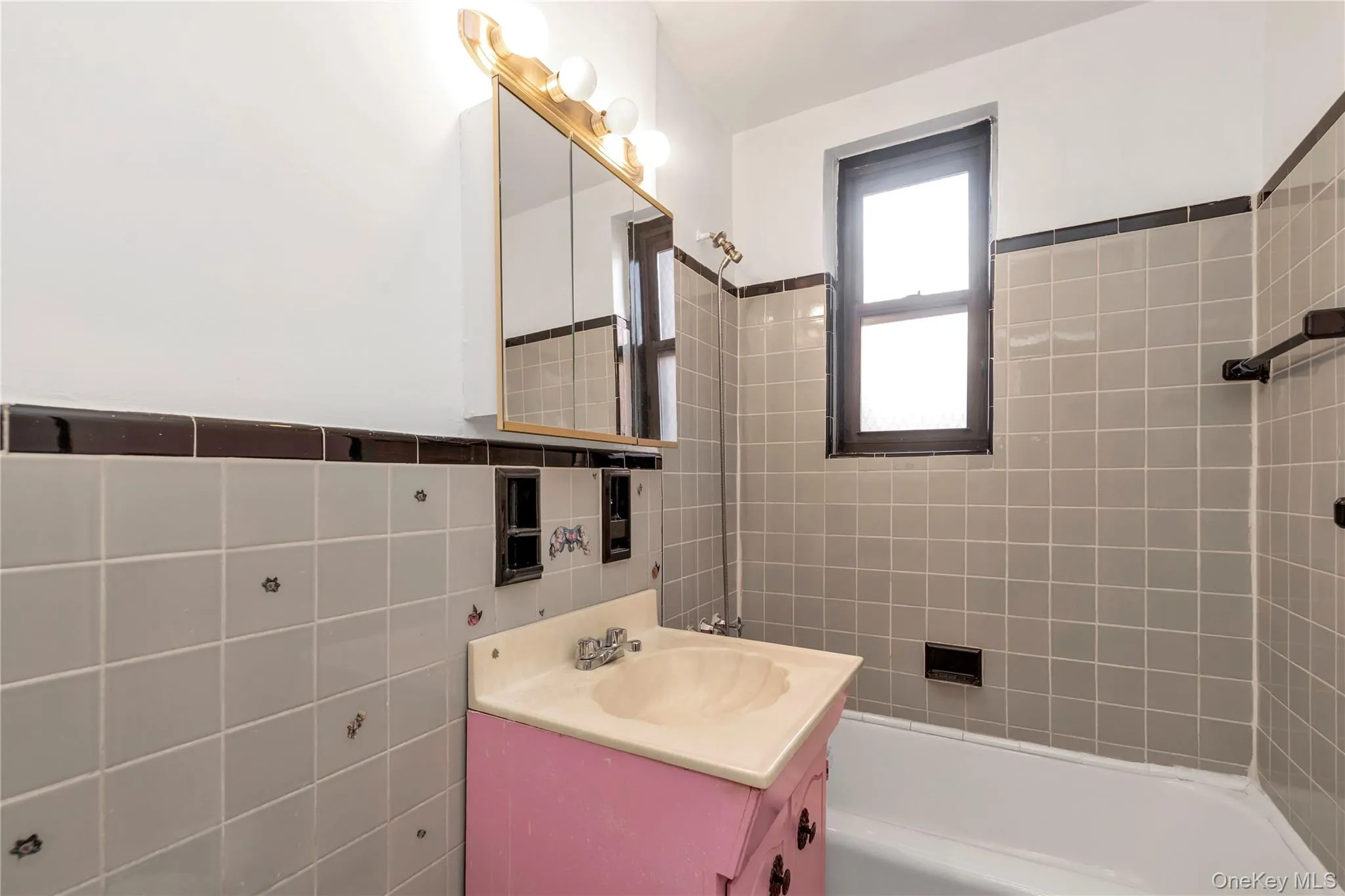 Full bathroom featuring tile walls, vanity, bathing tub / shower combination, and a wainscoted wall Full bathroom featuring tile walls, vanity, bathing tub / shower combination, and a wainscoted wall
