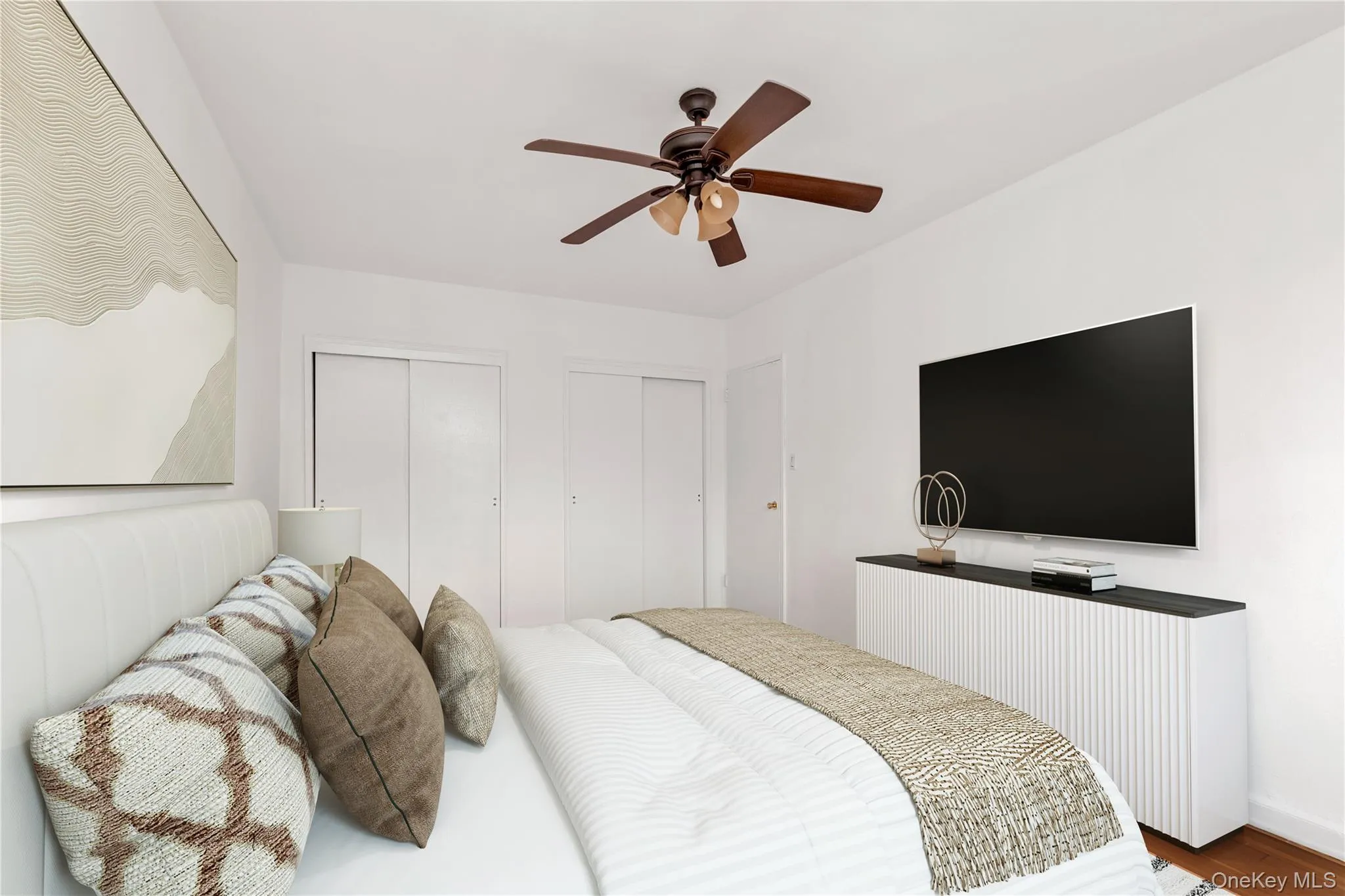Bedroom featuring multiple closets, wood finished floors, and a ceiling fan Bedroom featuring multiple closets, wood finished floors, and a ceiling fan