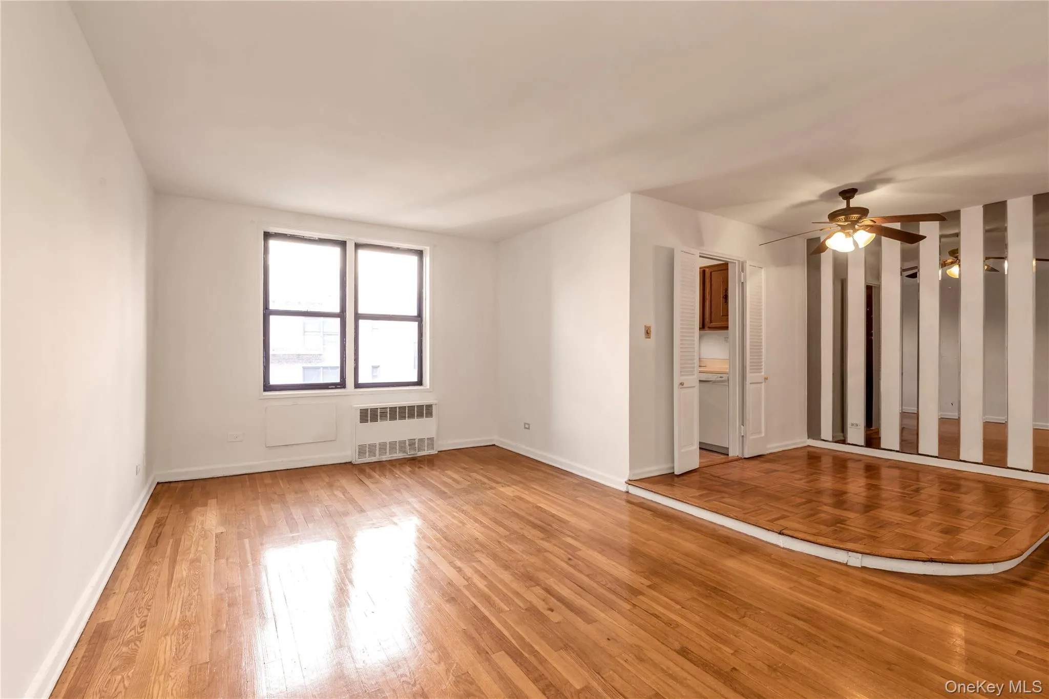 Spare room with light wood-type flooring, radiator, and a ceiling fan Spare room with light wood-type flooring, radiator, and a ceiling fan