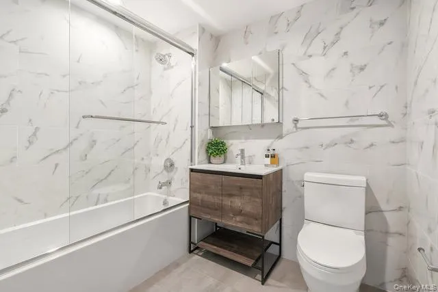 Bathroom with a combined bath / shower with marble appearance, vanity, and tile walls Bathroom with a combined bath / shower with marble appearance, vanity, and tile walls