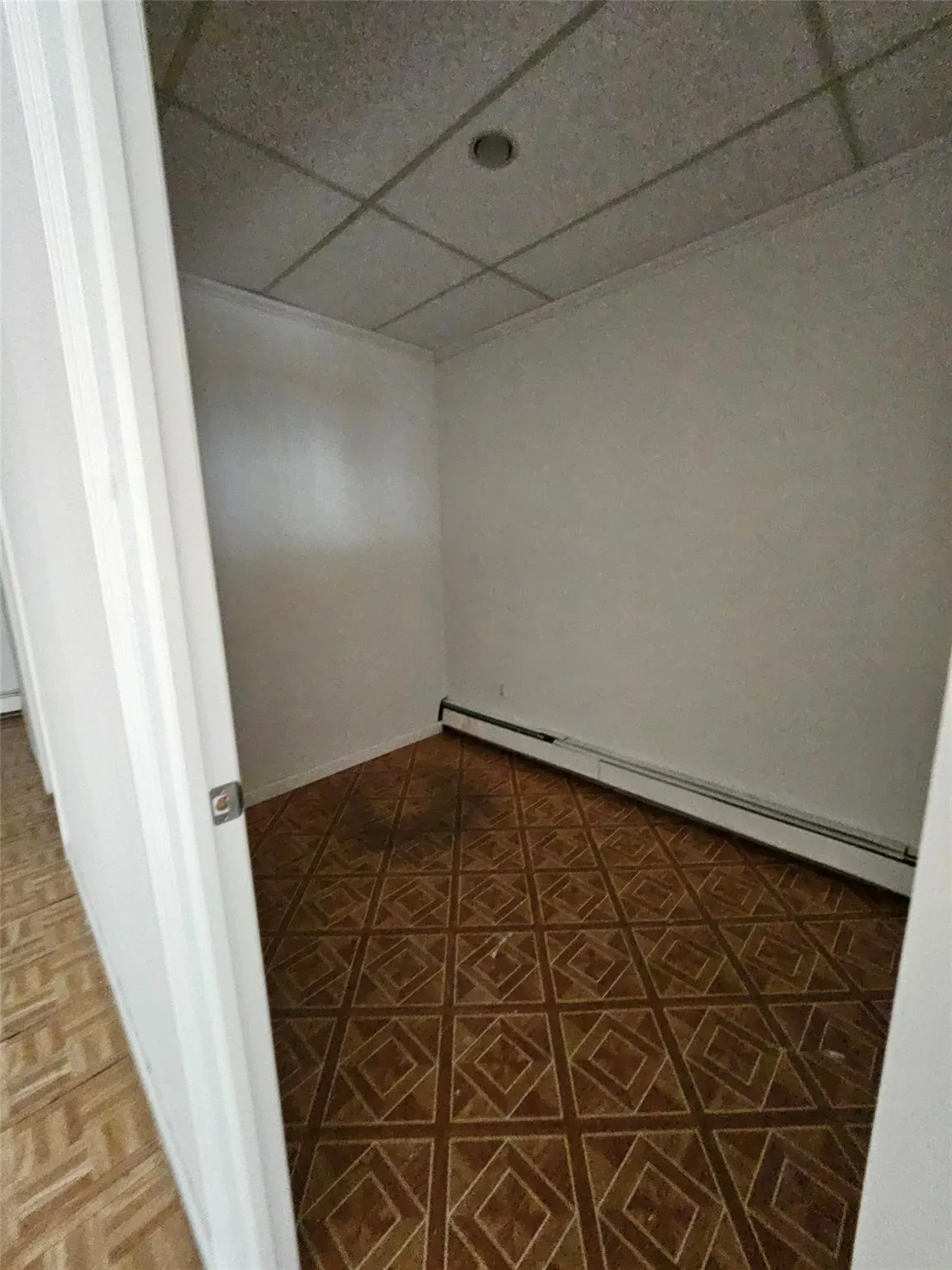 Empty room with a drop ceiling and a baseboard radiator Empty room with a drop ceiling and a baseboard radiator