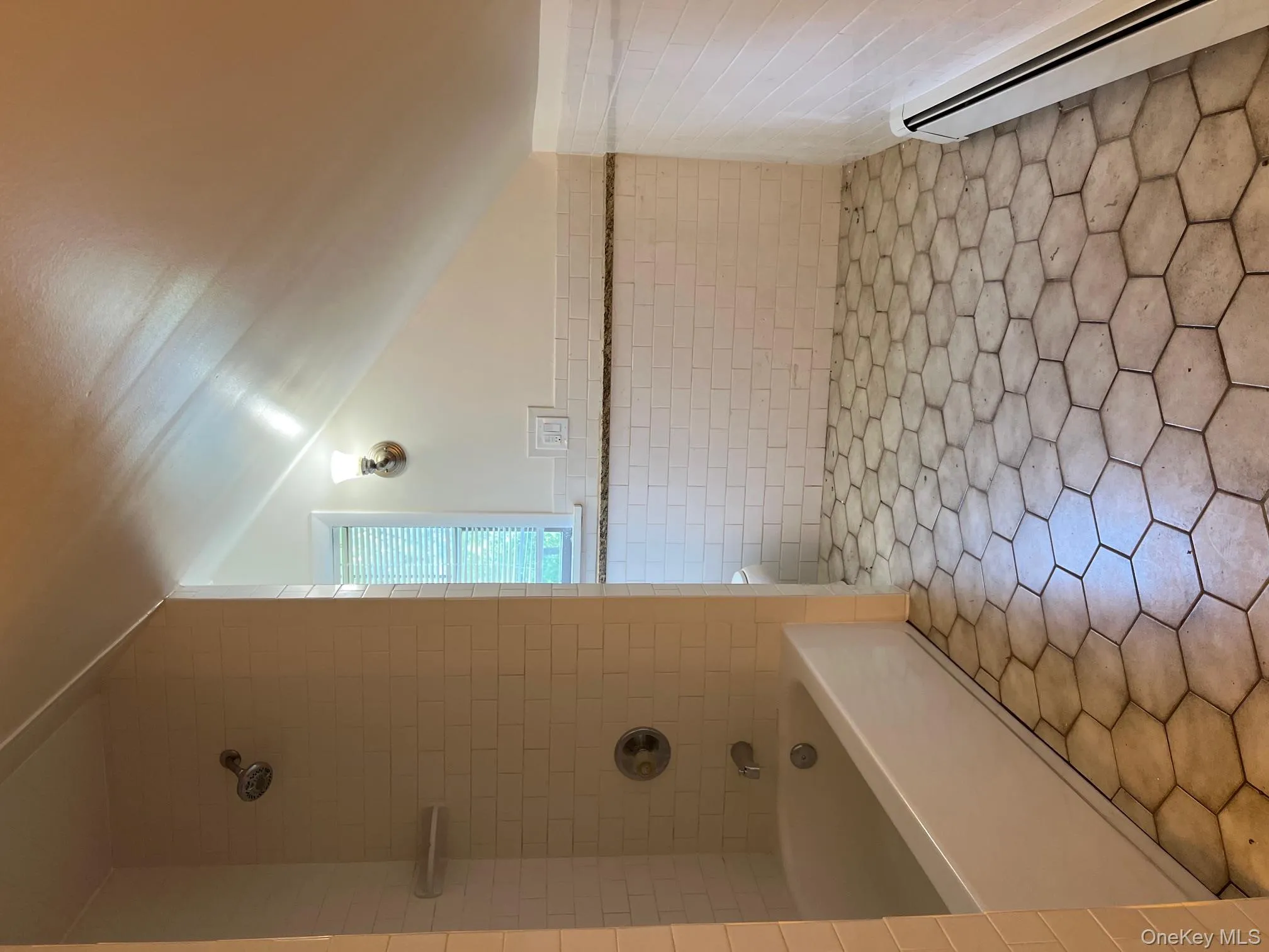 Very large full bathroom with baseboard heating, tile walls, a wainscoted wall, washtub / shower combination, and lofted ceiling Very large full bathroom with baseboard heating, tile walls, a wainscoted wall, washtub / shower combination, and lofted ceiling