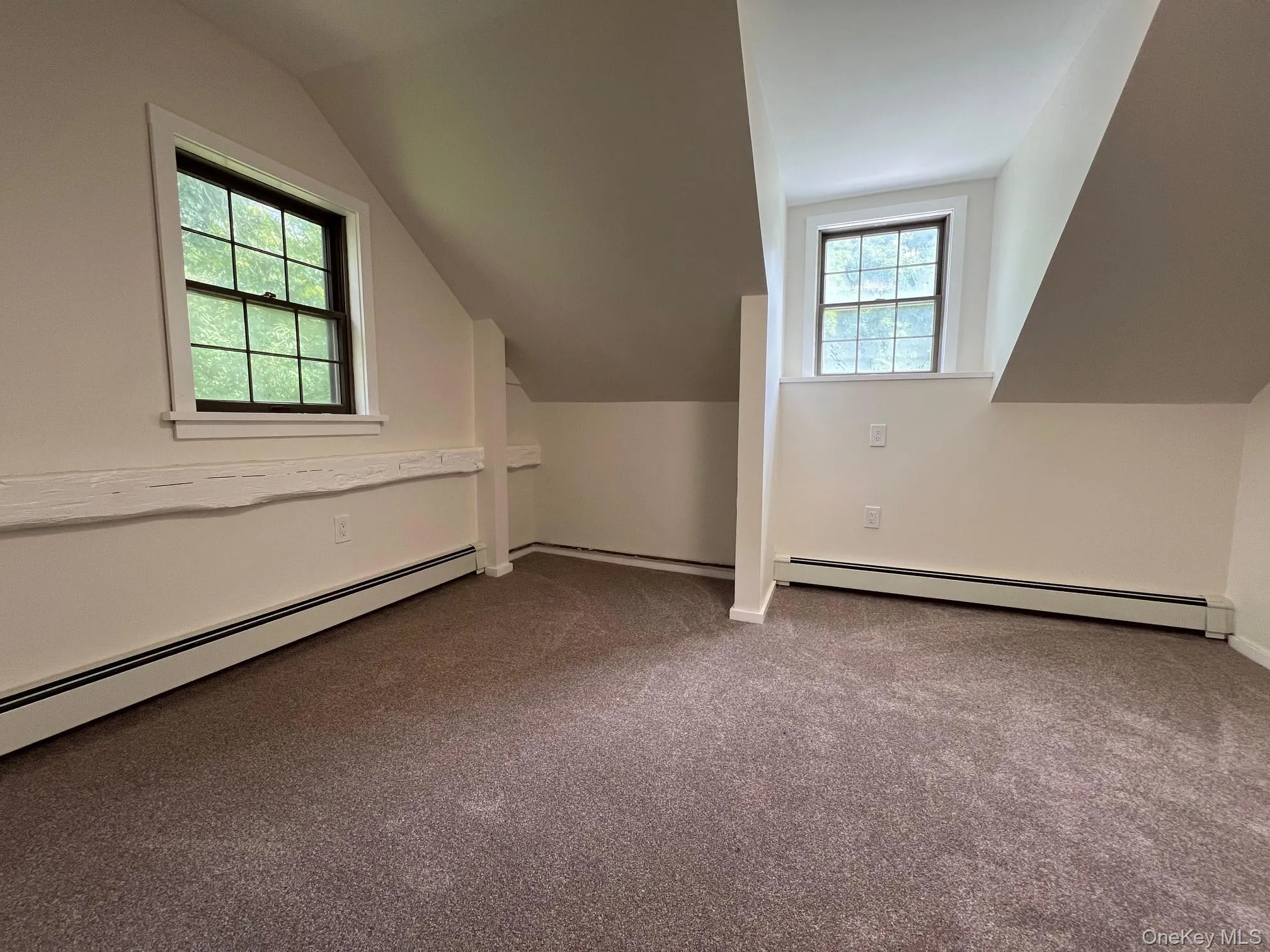Bonus room featuring lofted ceiling, a baseboard radiator, and dark carpet Bonus room featuring lofted ceiling, a baseboard radiator, and dark carpet